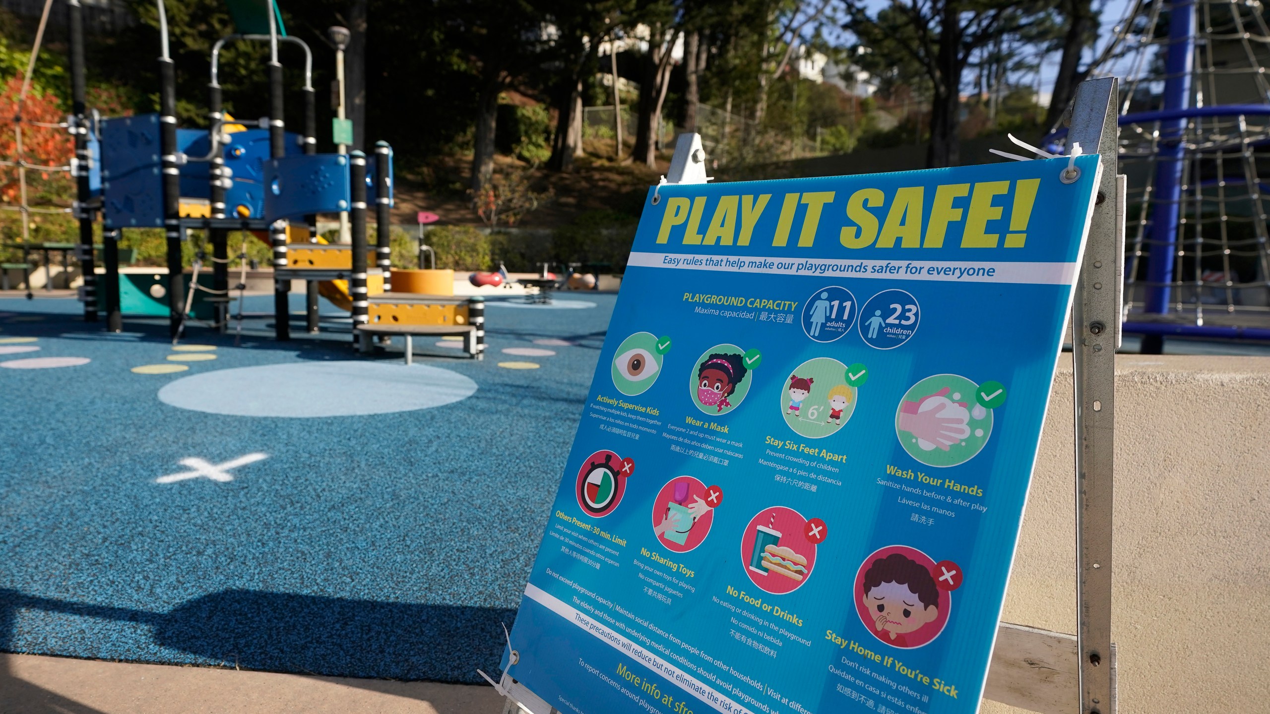 A sign is posted at Sunnyside Playground during the coronavirus outbreak in San Francisco, Wednesday, Dec. 9, 2020. California changed its rules overnight Wednesday to allow outdoors playgrounds to stay open in regions under strict stay-home orders. San Francisco Mayor London Breed applauded the change and said city playgrounds would reopen Thursday after shutting down earlier this week. (AP Photo/Jeff Chiu)