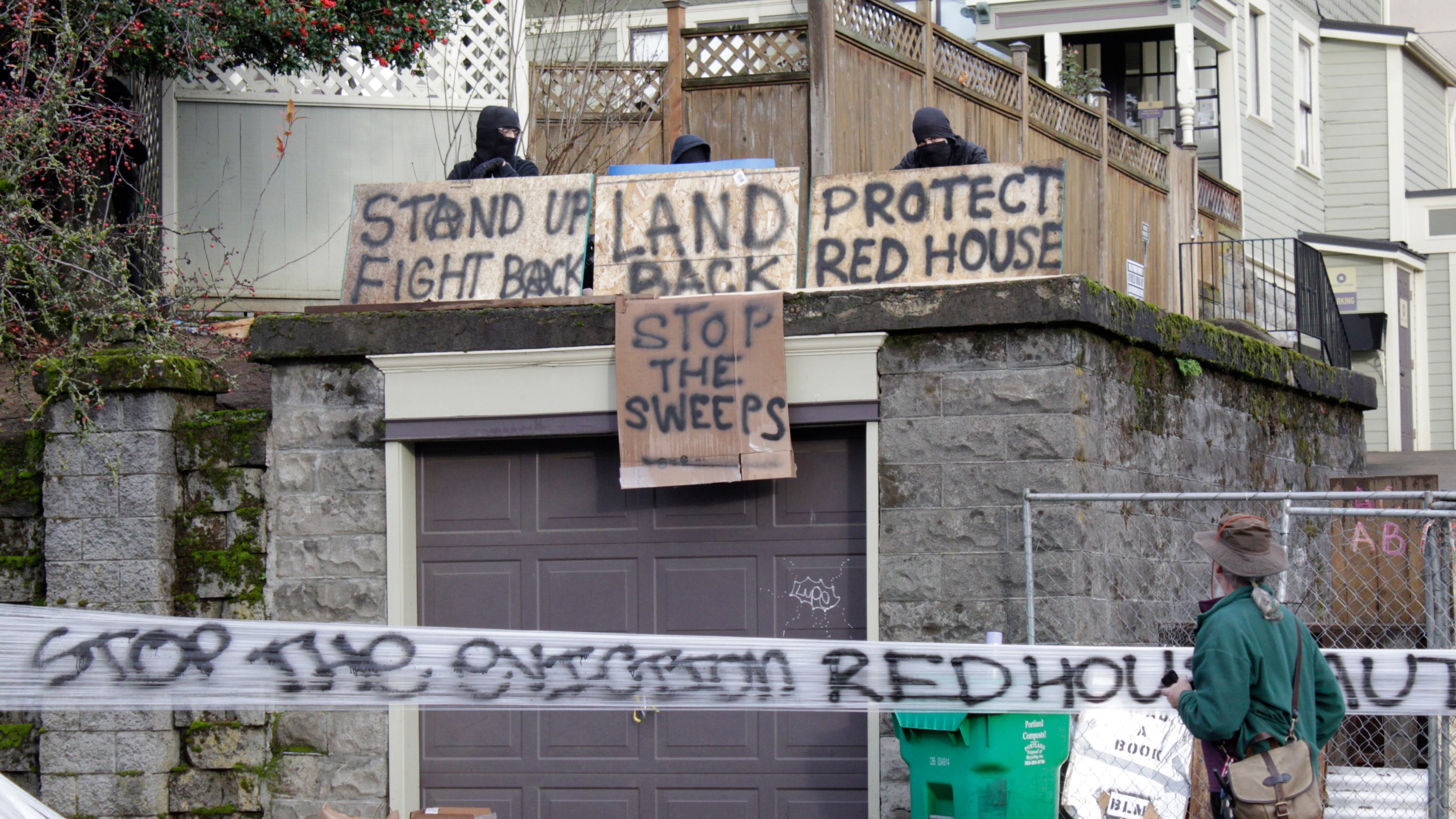 Masked protesters by an occupied home speak with a neighborhood resident opposed to their encampment and demonstration in Portland, Ore., on Dec. 9, 2020. (Gillian Flaccus / Associated Press)