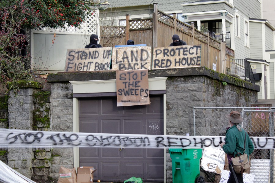 Masked protesters by an occupied home speak with a neighborhood resident opposed to their encampment and demonstration in Portland, Ore., on Dec. 9, 2020. (Gillian Flaccus / Associated Press)