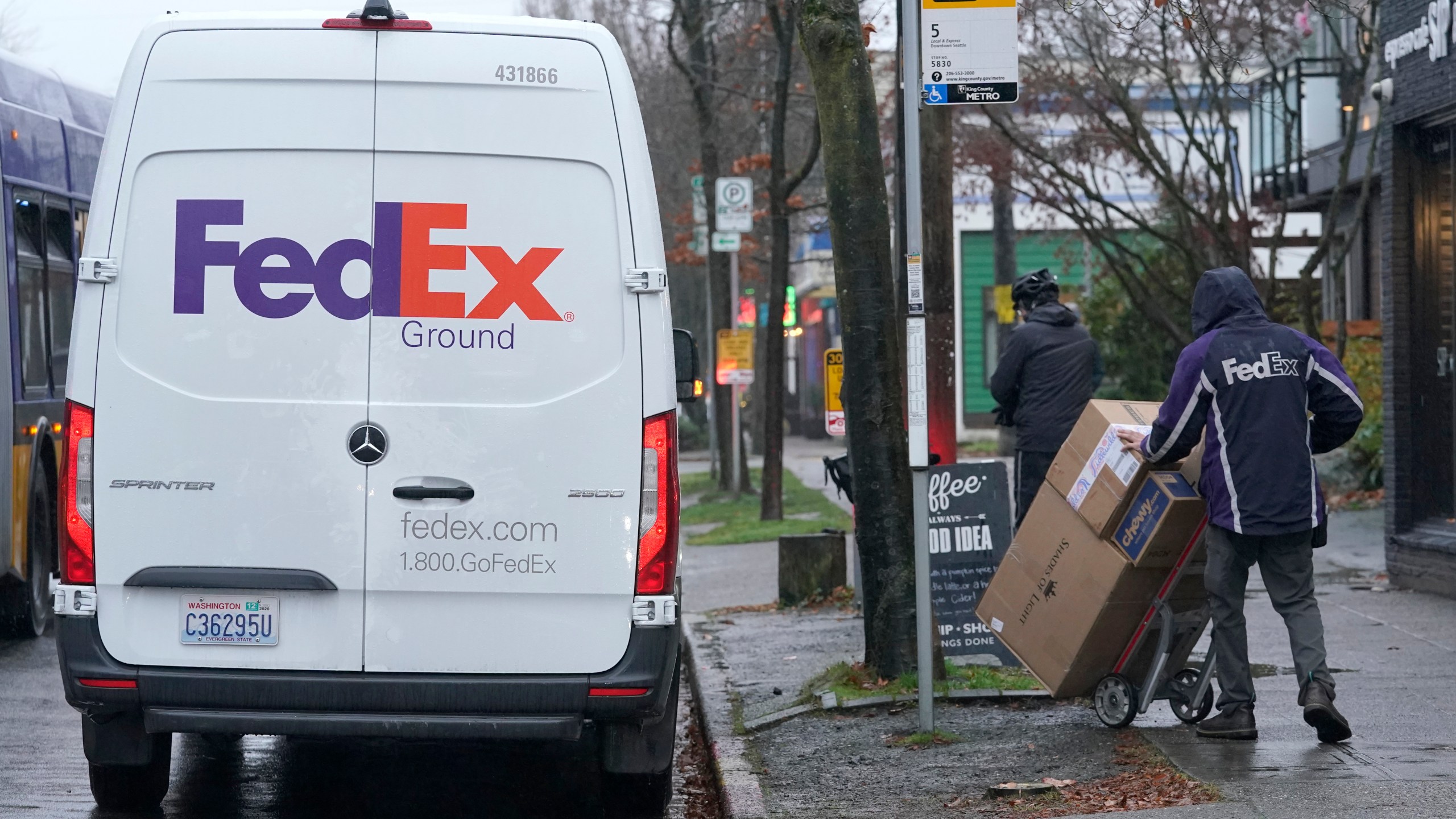 A driver with FedEx carries a package away from a van, Tuesday, Dec. 8, 2020, in Seattle. Store are warning online shoppers that if holiday purchases aren't made soon, they may not be delivered in time for Christmas. (Ted S. Warren/Associated Press)