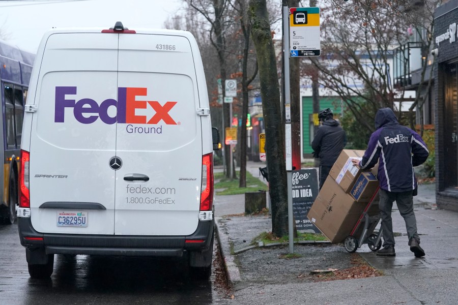 A driver with FedEx carries a package away from a van, Tuesday, Dec. 8, 2020, in Seattle. Store are warning online shoppers that if holiday purchases aren't made soon, they may not be delivered in time for Christmas. (Ted S. Warren/Associated Press)