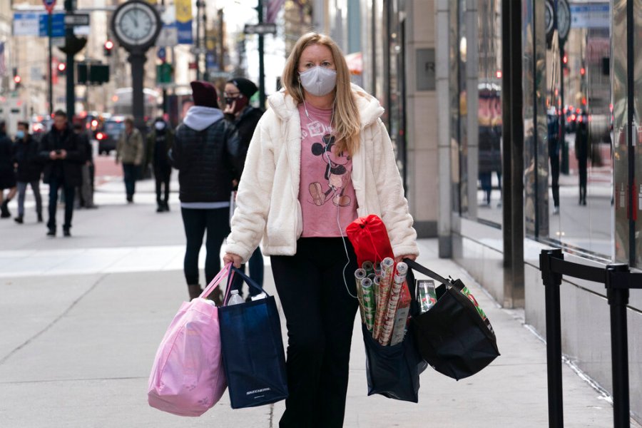 A woman carries shopping bags, Thursday, Dec. 10, 2020, in New York. (AP Photo/Mark Lennihan)