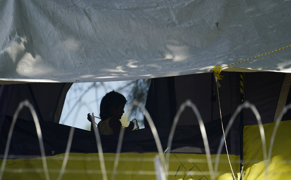 In this Nov. 18, 2020, file photo, a young girl plays in her family's tent at a camp of asylum seekers stuck at America's doorstep, in Matamoros, Mexico. Increasing numbers of parents and children are crossing the border, driven by violence and poverty in Central America and growing desperation in migrant camps in Mexico. U.S. Customs and Border Protection said Monday, Dec. 14, 2020 that it made 4,592 apprehensions of unaccompanied immigrant children in November, more than six times the figure in April. (AP Photo/Eric Gay File)