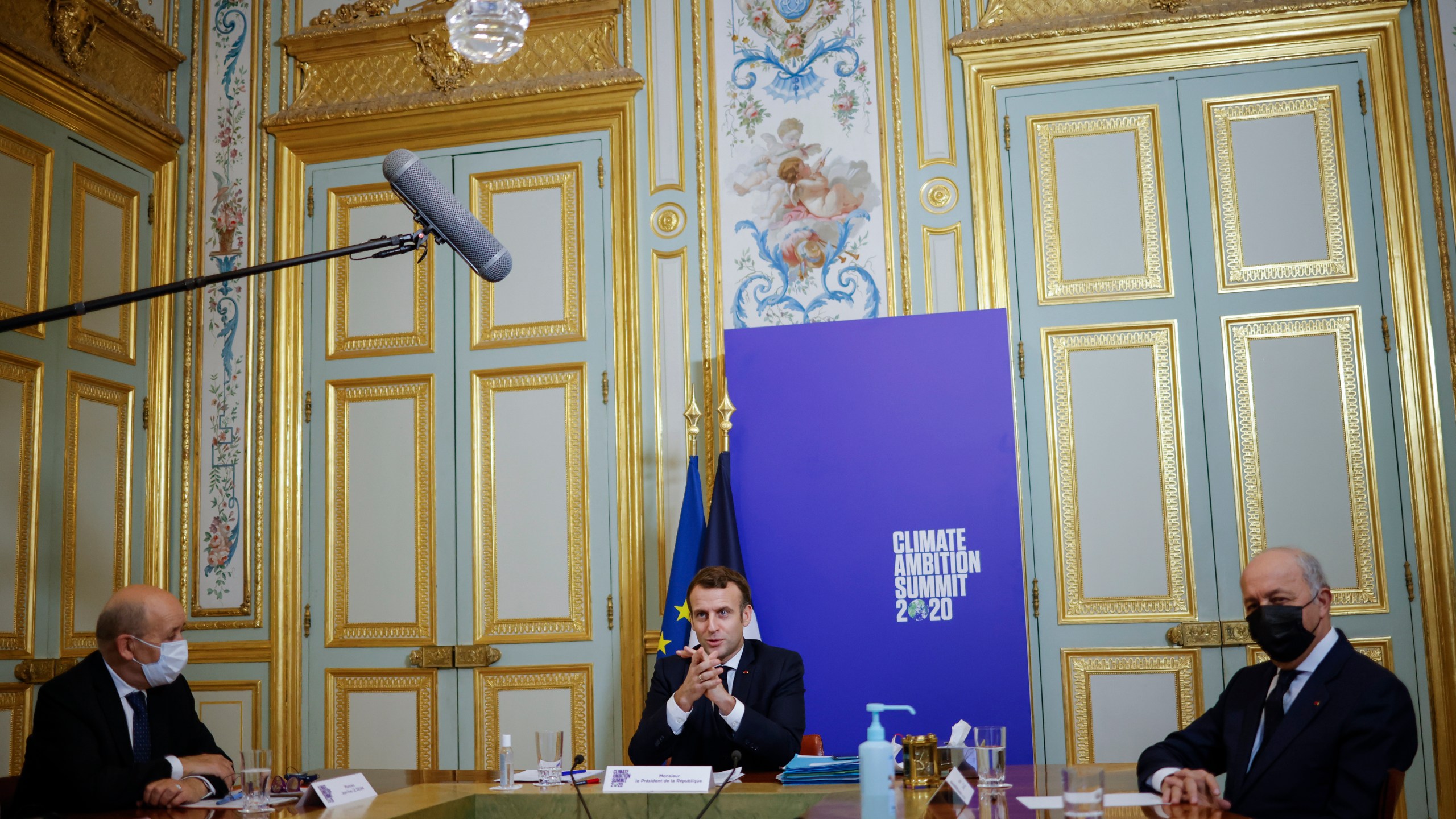 French President Emmanuel Macron, center flanked by French Foreign Minister Jean-Yves Le Drian, left, and President of the French Constitutional Council Laurent Fabius right, speaks during the Climate Ambition Summit 2020 video conference at the Elysee Palace in Paris, Saturday Dec.12, 2020. World leaders are staging a virtual gathering Saturday to celebrate the 5th anniversary of the Paris climate accord, which set a goal for keeping global temperatures from rising above levels that could have devastating consequences for mankind. (Yoan Valat, Pool via AP)