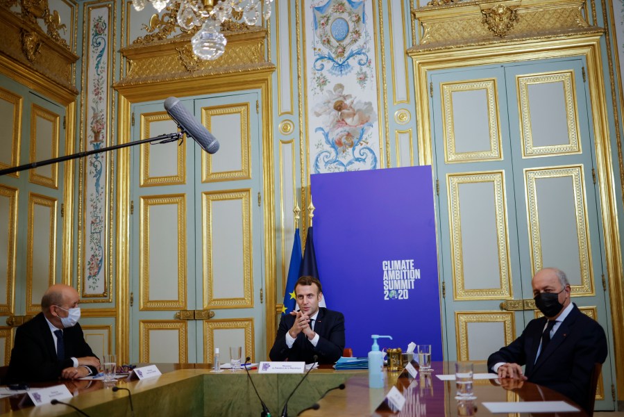 French President Emmanuel Macron, center flanked by French Foreign Minister Jean-Yves Le Drian, left, and President of the French Constitutional Council Laurent Fabius right, speaks during the Climate Ambition Summit 2020 video conference at the Elysee Palace in Paris, Saturday Dec.12, 2020. World leaders are staging a virtual gathering Saturday to celebrate the 5th anniversary of the Paris climate accord, which set a goal for keeping global temperatures from rising above levels that could have devastating consequences for mankind. (Yoan Valat, Pool via AP)