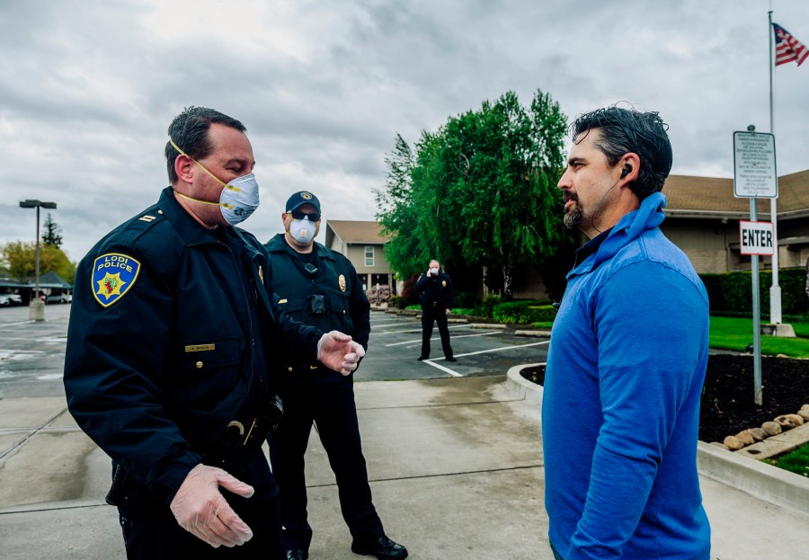 In this April 5, 2020, file photo, Lodi Police Capt. Sierra Brucia, left, meets with Pastor Jon Duncan of the Cross Culture Christian Center on Palm Sunday in Lodi, Calif. The church sued Gov. Gavin Newsom arguing his stay-at-home order violated their constitutional rights. In San Joaquin County, part of California's vast Central Valley that produces most of the country's fruits and vegetables, the coronavirus is the leading cause of death this year and things will only worsen as infections skyrocket and hospitals fill beyond capacity. Like most of California, the city of Lodi is under a broad shutdown order as Christmas approaches, and its residents and businesses are grappling with how to stay safe while keeping their economy operating. (Daniel Kim/The Sacramento Bee via AP)