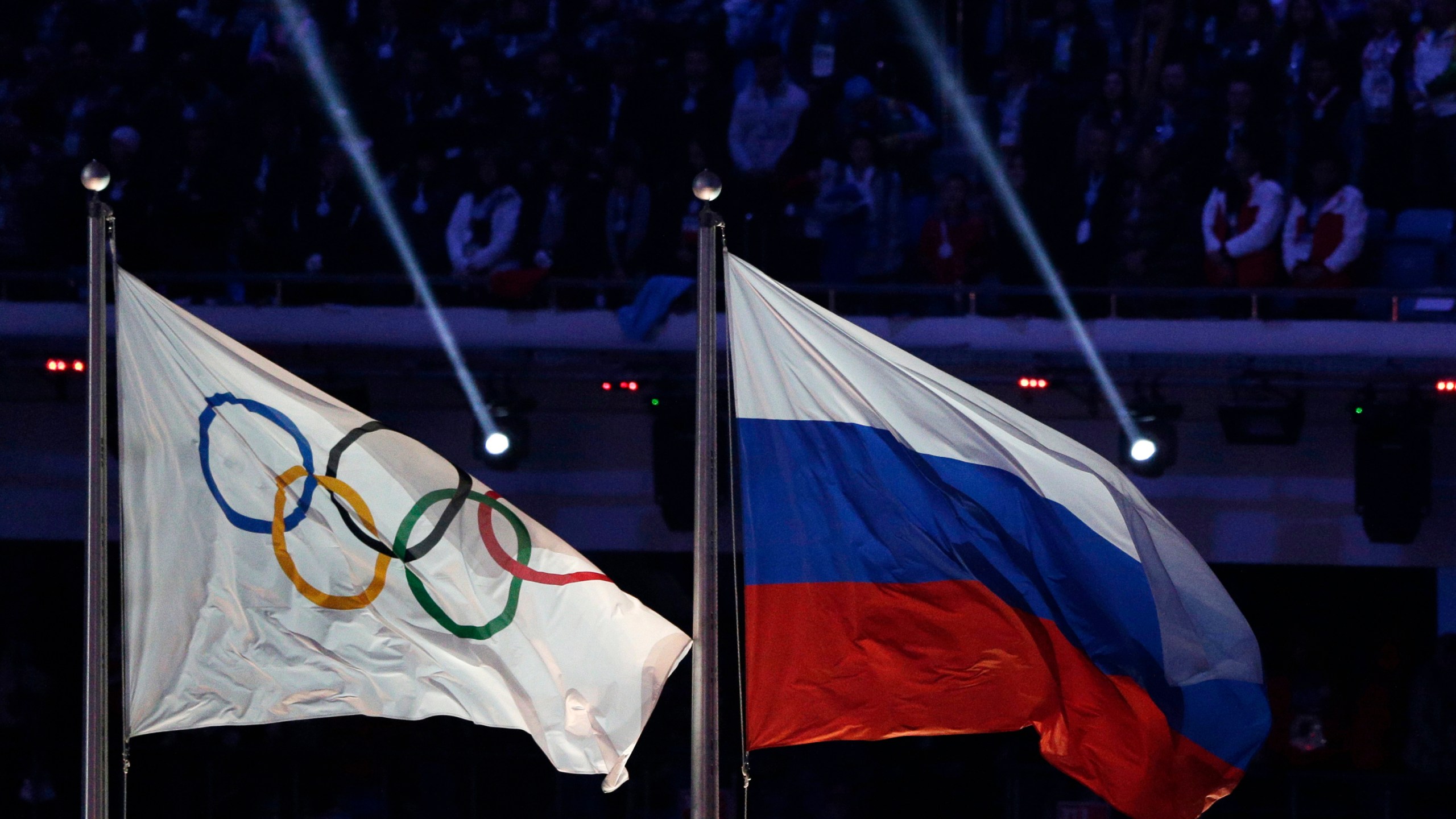 In this Feb. 23, 2014 file photo the Russian national flag, right, flies after it is hoisted next to the Olympic flag during the closing ceremony of the 2014 Winter Olympics in Sochi, Russia. (Matthias Schrader/AP Photo)