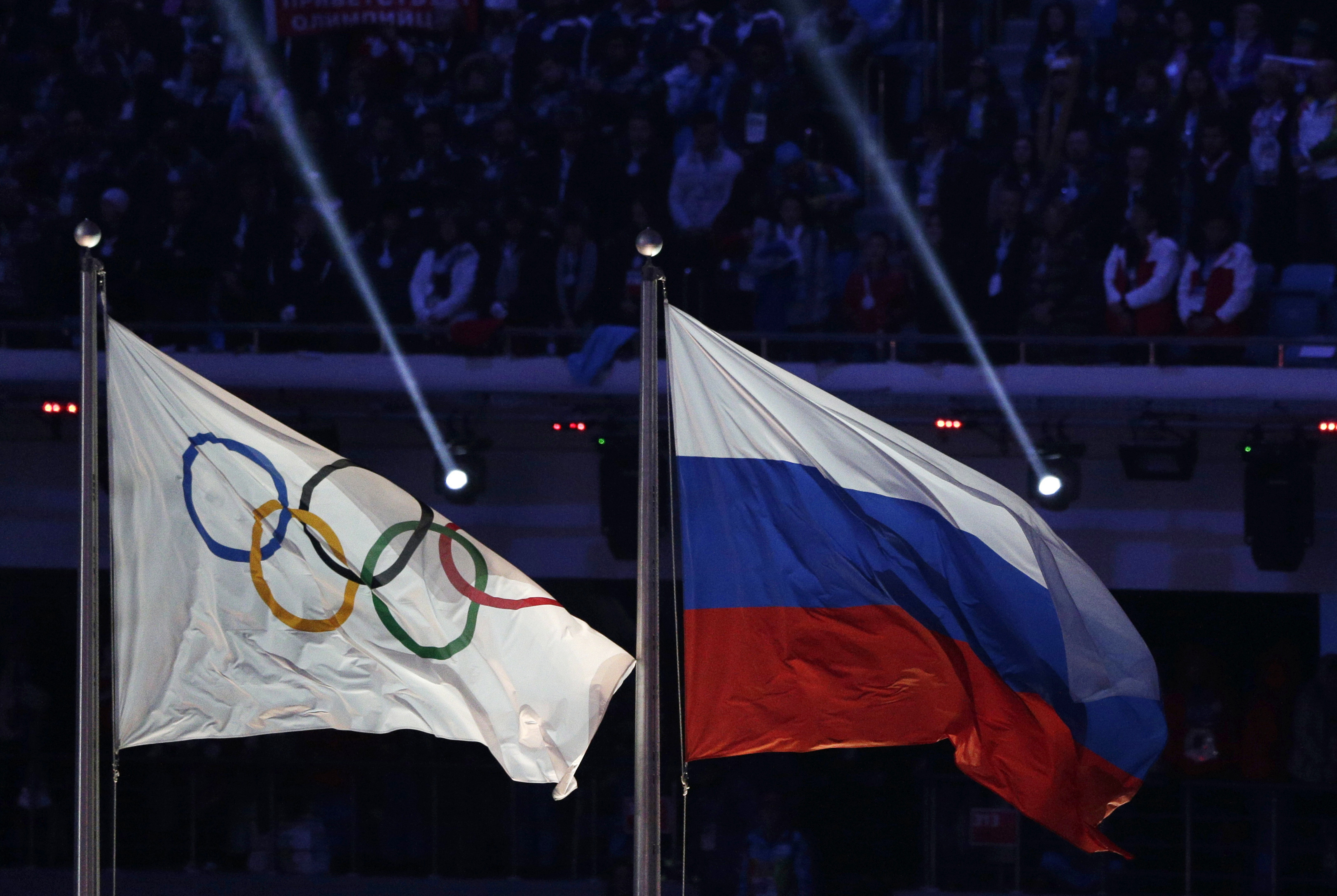 In this Feb. 23, 2014 file photo the Russian national flag, right, flies after it is hoisted next to the Olympic flag during the closing ceremony of the 2014 Winter Olympics in Sochi, Russia. (Matthias Schrader/AP Photo)