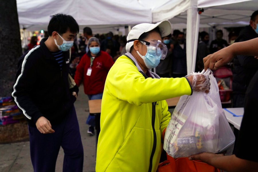 A woman receives a bag of groceries at a food bank at the Los Angeles Boys & Girls Club in the Lincoln Heights neighborhood of Los Angeles, Thursday, Dec. 17, 2020. (AP Photo/Jae C. Hong)