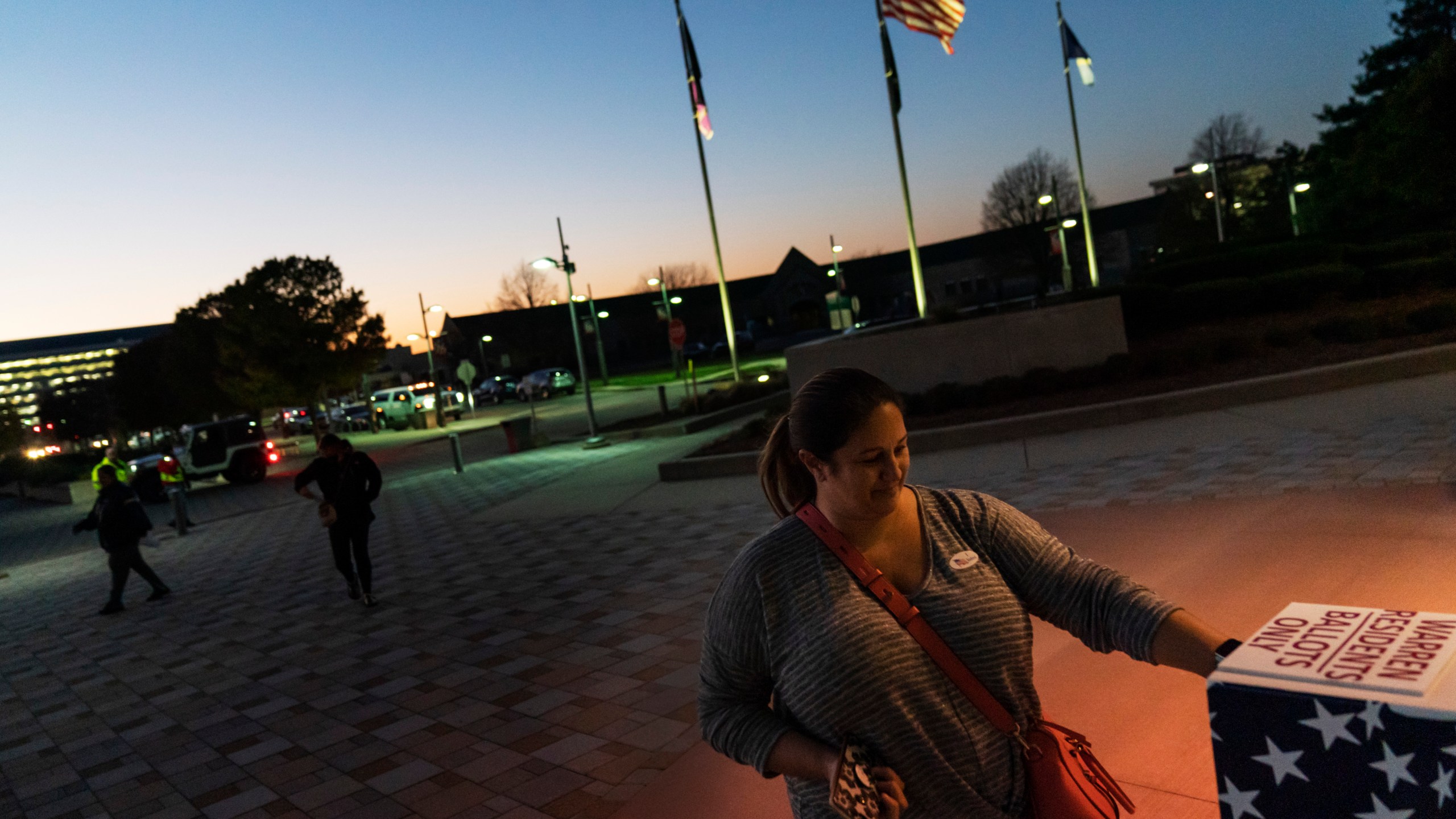 In this Tuesday, Nov. 3, 2020 file photo, Wendy Gill inserts her absentee ballot at a drop-off box as the sun sets on Election Day outside City Hall in Warren, Mich. (David Goldman/AP Photo)