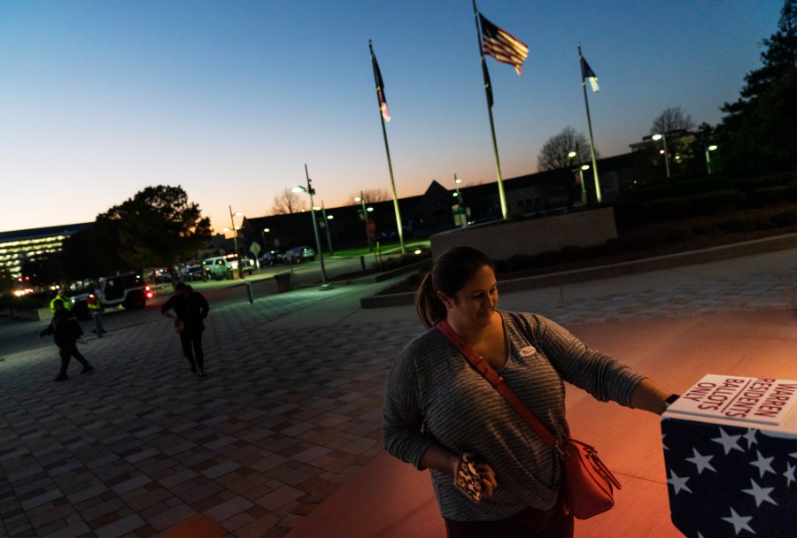 In this Tuesday, Nov. 3, 2020 file photo, Wendy Gill inserts her absentee ballot at a drop-off box as the sun sets on Election Day outside City Hall in Warren, Mich. (David Goldman/AP Photo)