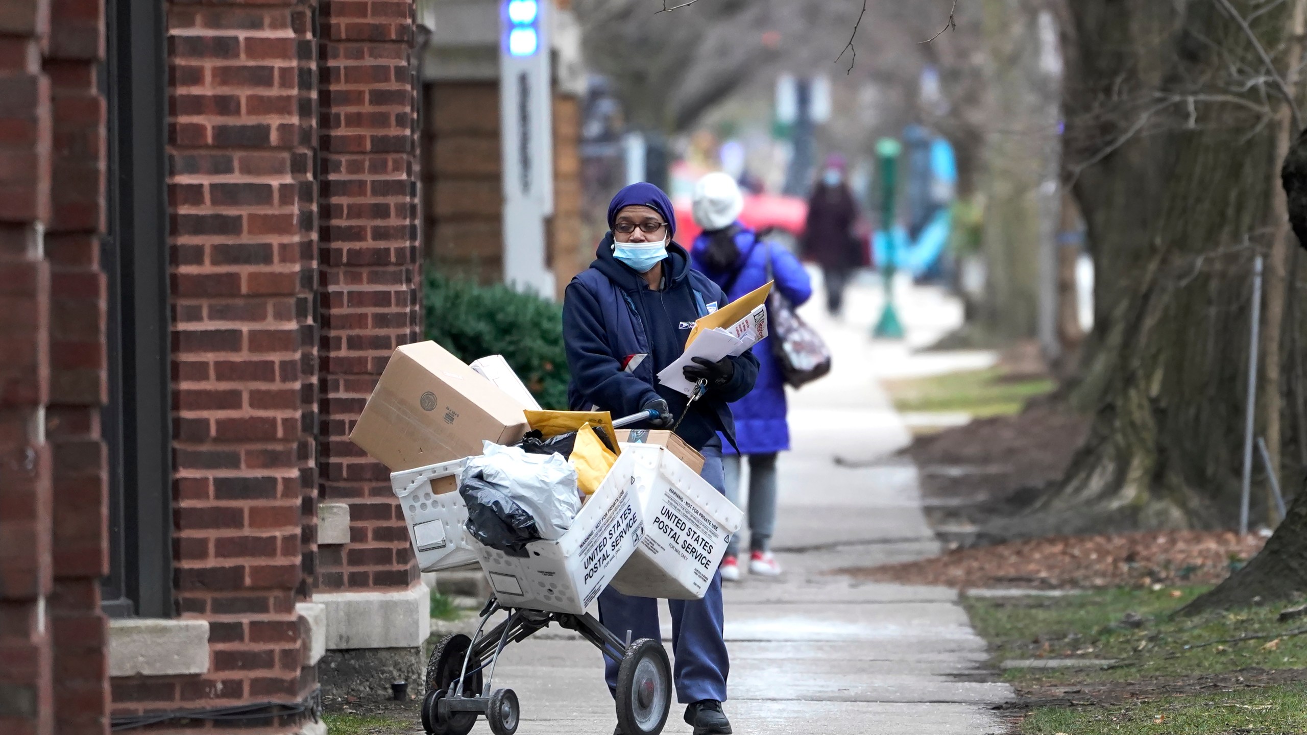 A U.S. postal worker delivers packages, boxes and letters Dec. 22, 2020, along her route in the Hyde Park neighborhood of Chicago on Dec. 22, 2020. (Charles Rex Arbogast)