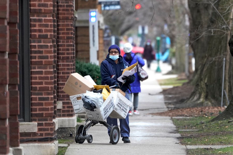 A U.S. postal worker delivers packages, boxes and letters Dec. 22, 2020, along her route in the Hyde Park neighborhood of Chicago on Dec. 22, 2020. (Charles Rex Arbogast)