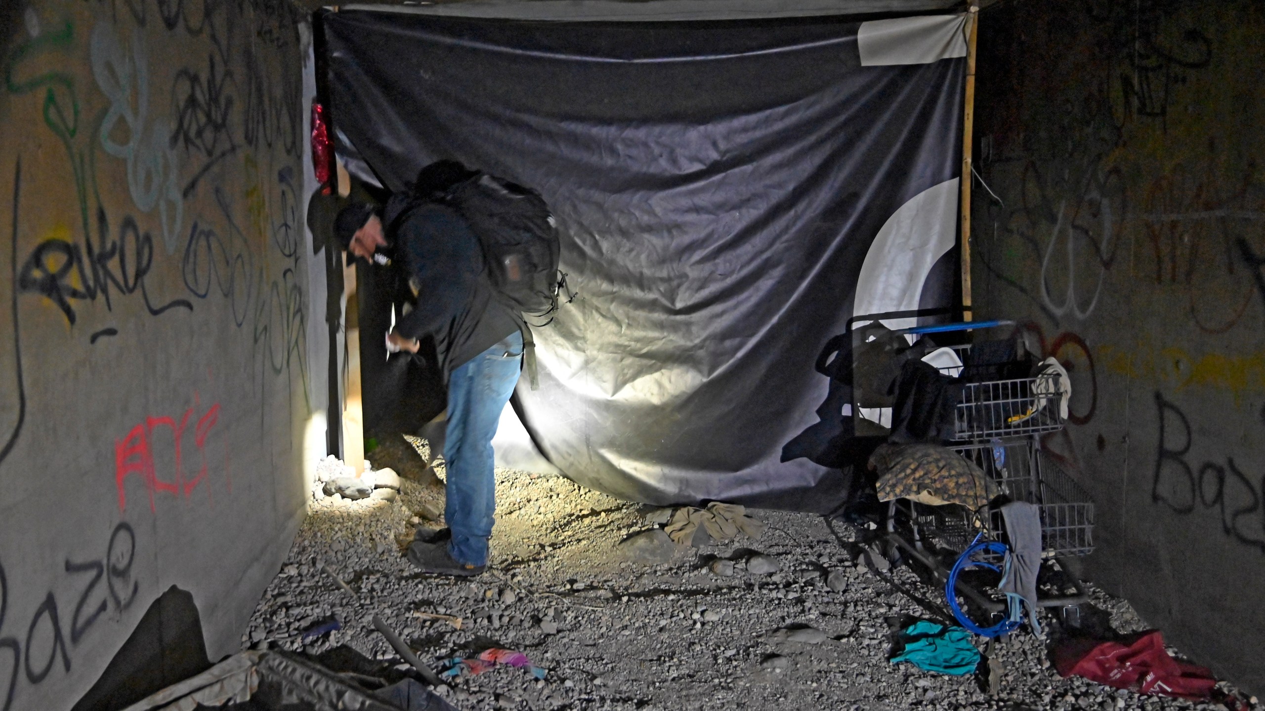 In this Dec. 5, 2020, file photo, Paul Vautrinot of Shine a Light passes though personal belongs as he provides outreach in the underground tunnels to offer counseling, food and water to the homeless living beneath the city in Las Vegas. (David Becker/AP Photo)