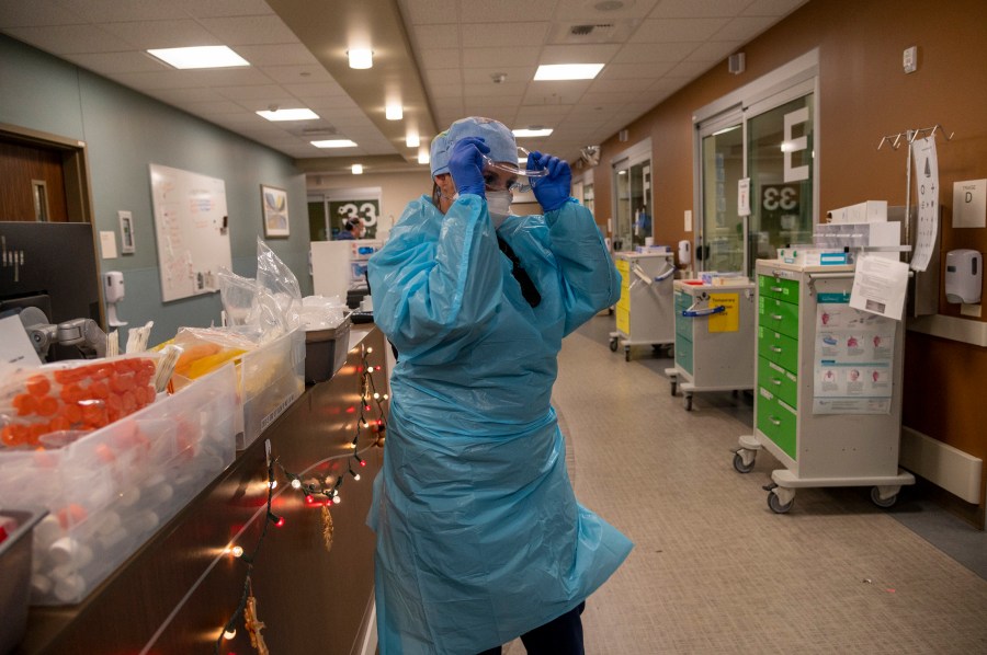 Registered Nurse Allison Shiftar puts on protective glasses as she gets ready to go into one of the triage rooms to care for a COVID-19 positive patient in the emergency department at Sutter Roseville Medical Center in Roseville, Calif. on Dec. 22, 2020. (Renee C. Byer/The Sacramento Bee via AP, Pool)