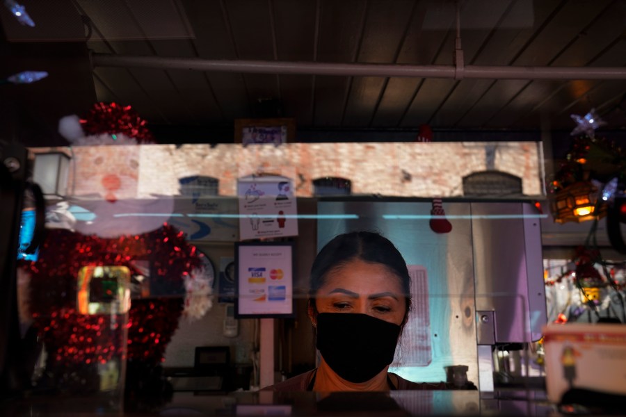 Debbie Briano, a fourth-generation owner of Mexican restaurant, El Rancho Grande, works in her restaurant on Olvera Street in downtown Los Angeles, Wednesday, Dec. 16, 2020. Briano still decorated her cafe like she normally would at Christmas. She bought poinsettias, put up a real tree, hung tinsel, lights, and strung little snowmen and Santa Claus above her window. "I had to do that to feel normal," she said. "I' m not going to let COVID take away our Christmas magic." (Jae C. Hong / Associated Press)