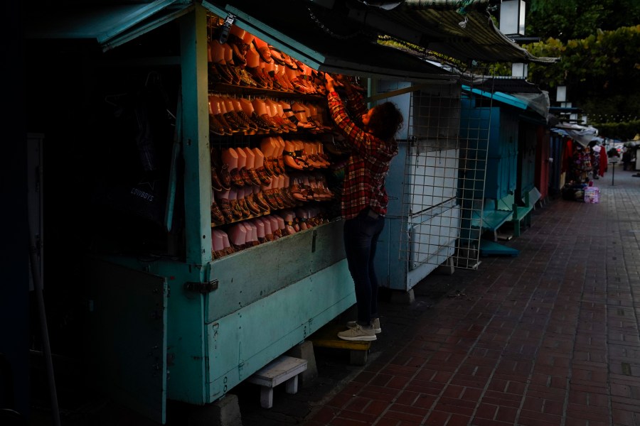 A merchant closes her shop for the day on Olvera Street in downtown Los Angeles, Tuesday, Dec. 15, 2020. Olvera Street, known as the birthplace of Los Angeles, has been particularly hard hit by the coronavirus pandemic, with shops and restaurants closed and others barely hanging on. Only a handful of businesses remain open on weekdays as tourism has cratered and downtown offices are closed and festive events held throughout the year have been canceled. (Jae C. Hong / Associated Press)