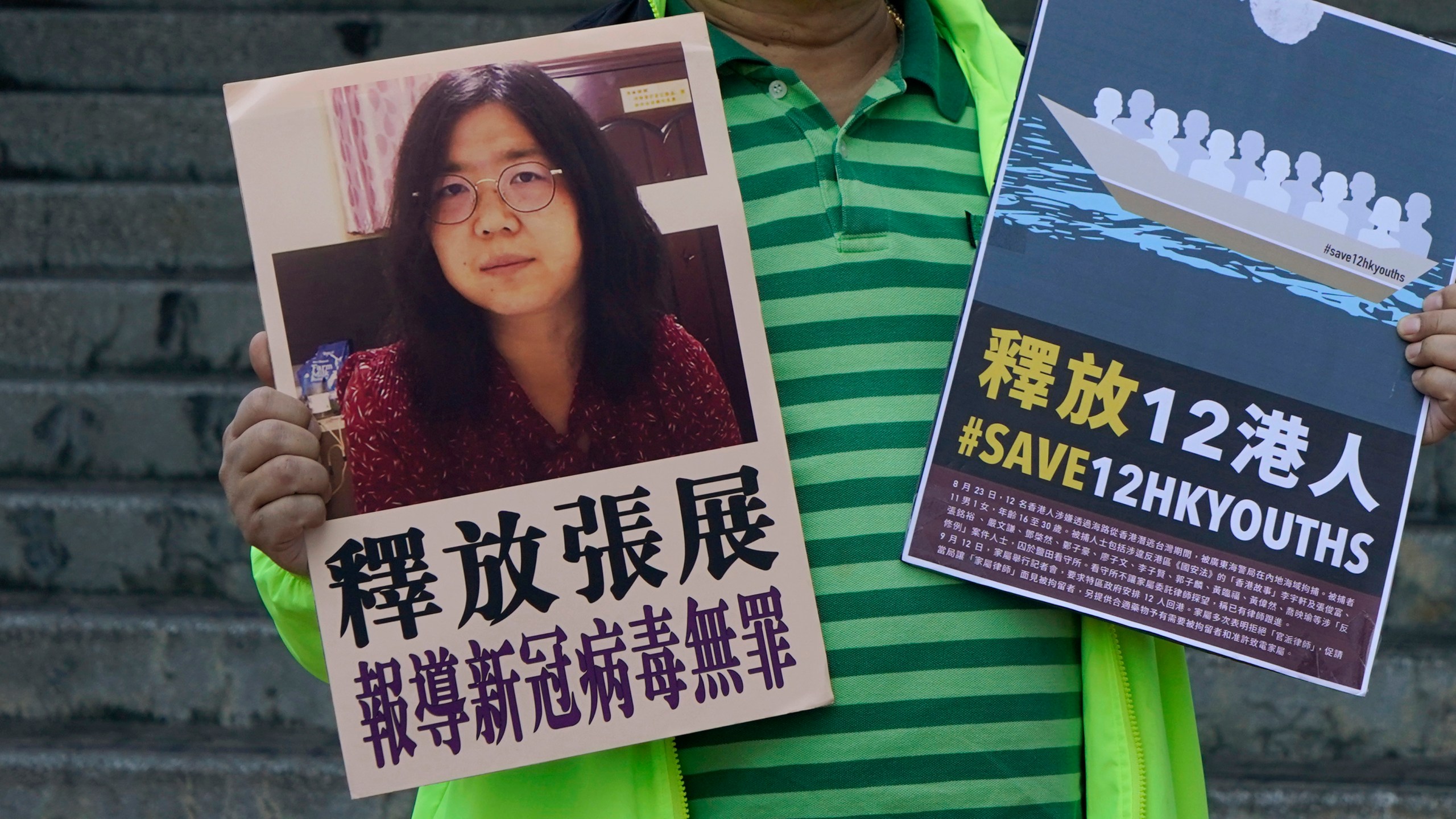 A pro-democracy activist holds placards with the picture of Chinese citizen journalist Zhang Zhan outside the Chinese central government's liaison office, in Hong Kong, Monday, Dec. 28, 2020. (Kin Cheung/AP Photo)