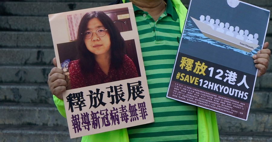 A pro-democracy activist holds placards with the picture of Chinese citizen journalist Zhang Zhan outside the Chinese central government's liaison office, in Hong Kong, Monday, Dec. 28, 2020. (Kin Cheung/AP Photo)