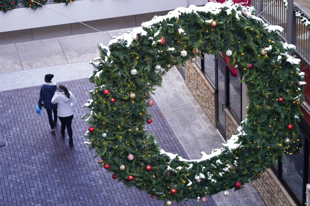 Shoppers wear face masks while in search of after-Christmas bargains in shops in the Denver Pavilions Tuesday, Dec. 29, 2020, in downtown Denver. (AP Photo/David Zalubowski)