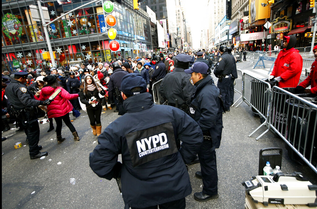 In this Dec. 31, 2014, file photo, New York Police Department counterterrorism officers, foreground, armed with an explosives detection device, far right, watch as other police officers inspect revelers entering a cordoned off area in Times Square in New York, on New Years Eve. (AP Photo/Kathy Willens, File)