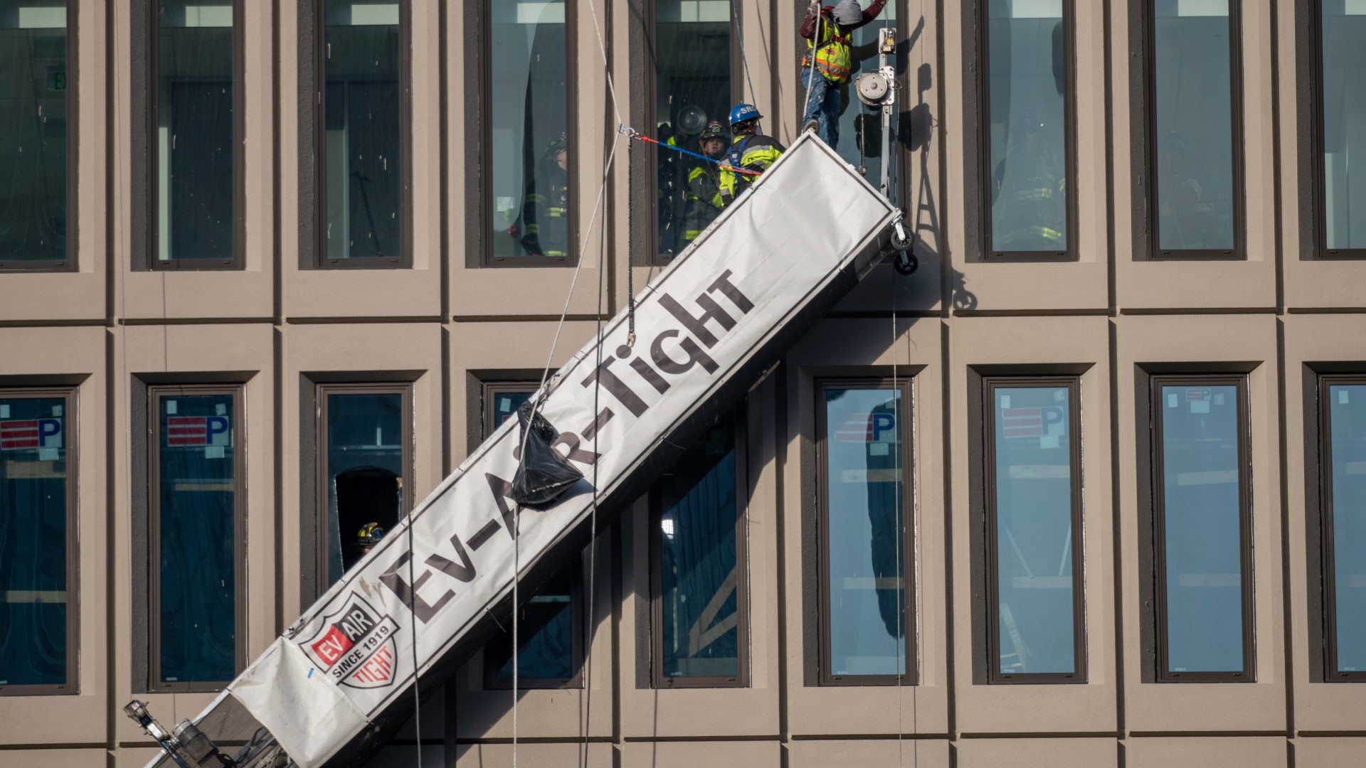 A worker stands on the end of a dangling scaffold as he waits to be rescued following an explosion at Baltimore Gas and Electric's offices, Wednesday, Dec. 23, 2020. Twenty-one of the victims were brought to area hospitals following the explosion with a partial roof collapse. The city’s fire department tweeted that at least nine of the victims were in critical condition, while another was in serious condition. (Jerry Jackson/The Baltimore Sun via AP)