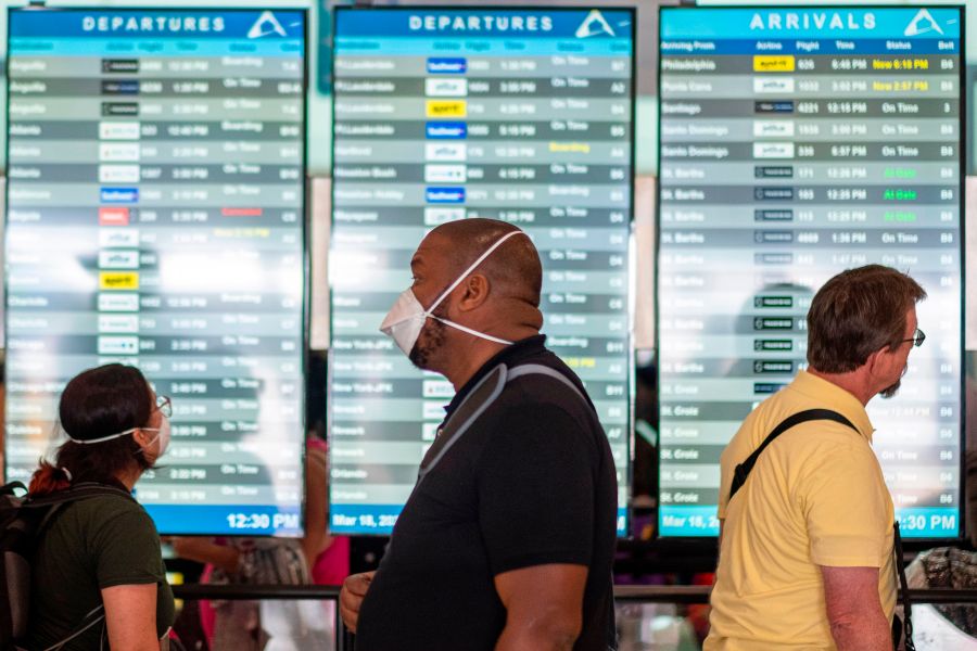 Travelers wearing masks wait in line at a security checkpoint at the Luis Munoz Marin International Airport in San Juan, Puerto Rico, on March 18, 2020. (Ricardo Arduengo / AFP / Getty Images)