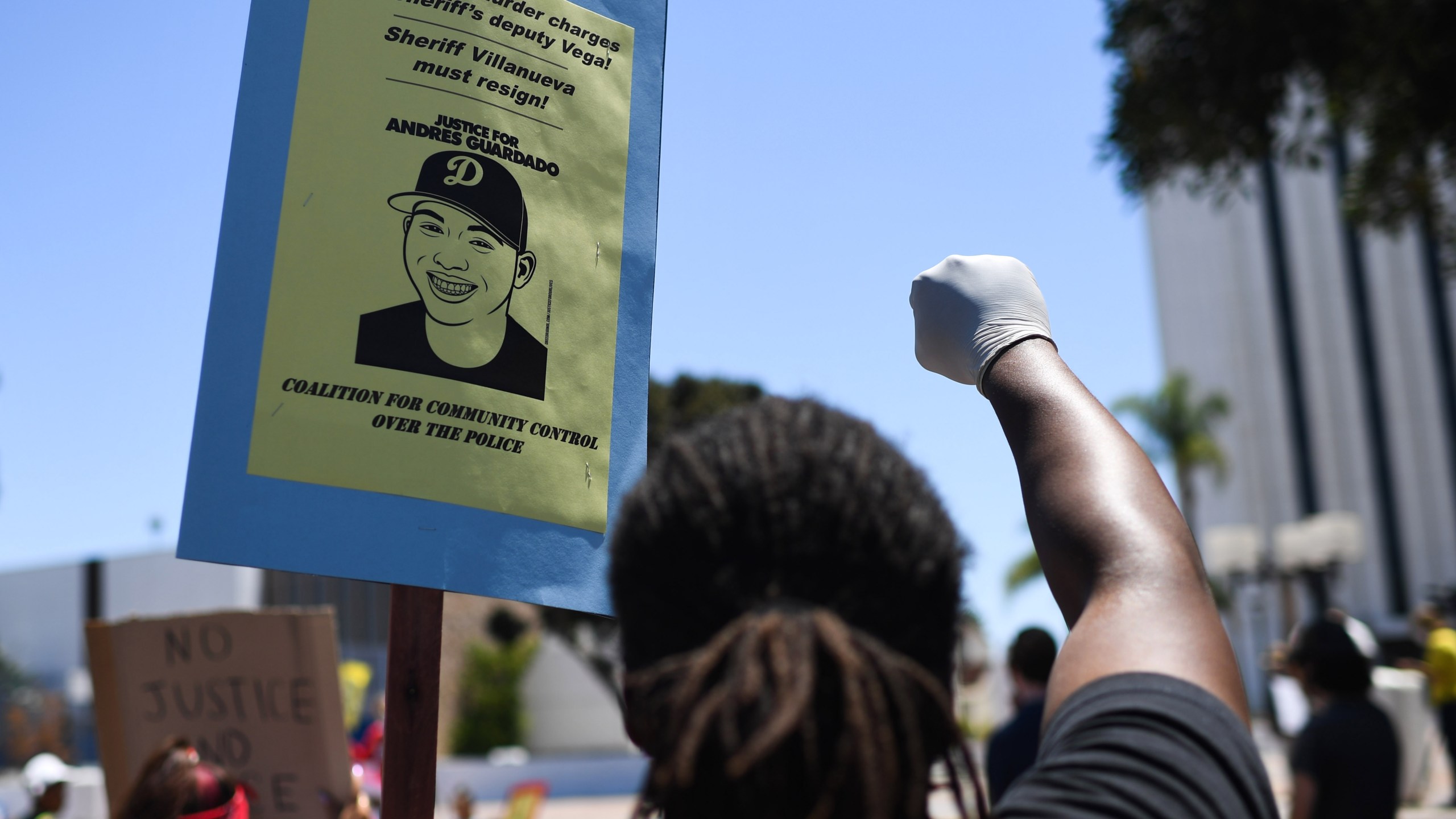 A person holds up a placard and a gloved fist during a protest in the Compton area calling for Los Angeles Sheriff's deputies to be held accountable for the shooting death of 18-year-old security guard Andres Guardado, on July 11, 2020. (ROBYN BECK/AFP via Getty Images)