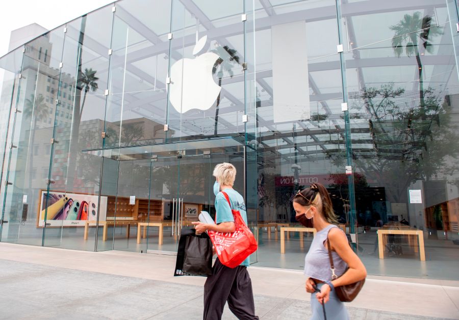 People wearing a mask walk by a closed Apple Store in Santa Monica, California, on July 28, 2020. (VALERIE MACON/AFP via Getty Images)