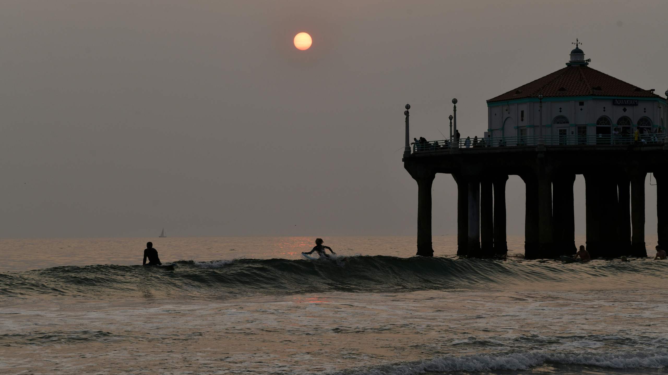 Surfers sit in the water at sunset during a heat wave on September 7, 2020 in Manhattan Beach, California. (Chris Delmas/AFP via Getty Images)