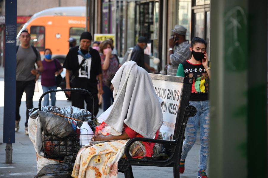 A homeless person sits on a bus bench in downtown Los Angeles on Oct. 2, 2020, amid the coronavirus COVID-19 pandemic. (Robyn Beck / AFP / Getty Images)