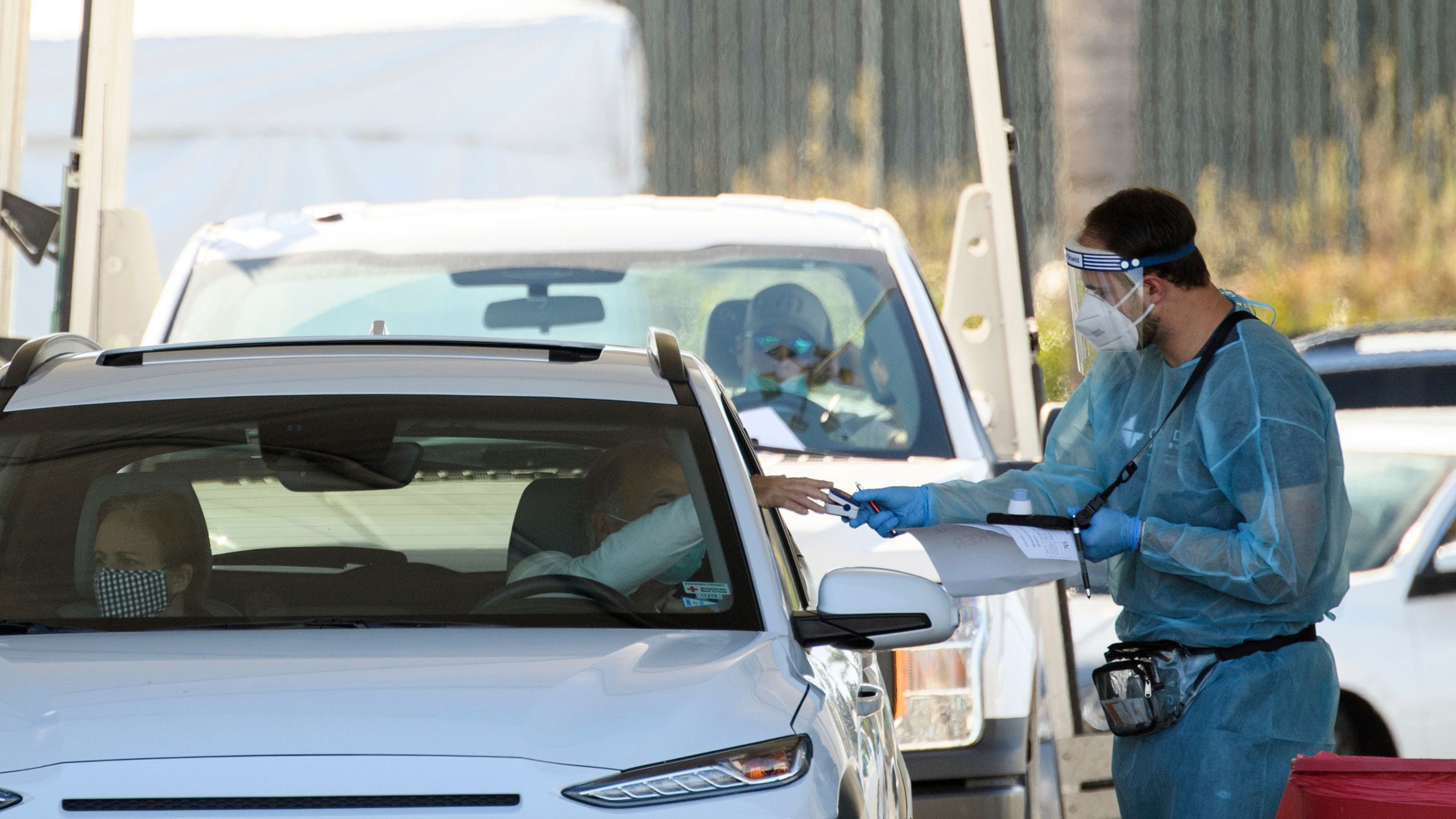 A COVID-19 testing site staff member uses a pulse oximeter to screen a driver at a drive-up testing site at the Orange County Fairgrounds in Costa Mesa on Nov. 17, 2020. (Patrick T. Fallon/AFP via Getty Images)