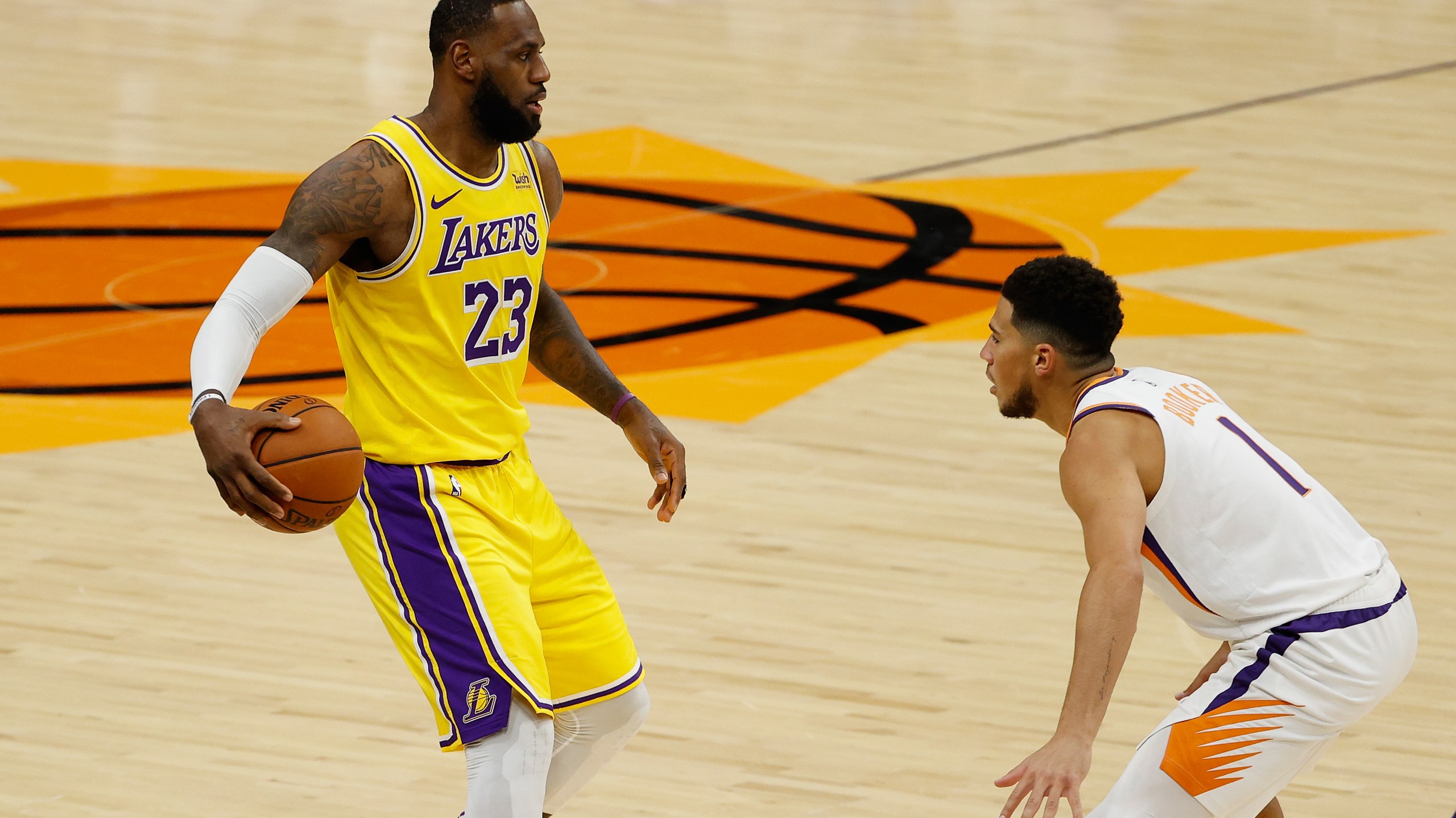 LeBron James #23 of the Los Angeles Lakers handles the ball against Devin Booker #1 of the Phoenix Suns during the NBA preseason game at Talking Stick Resort Arena on Dec. 18, 2020, in Phoenix, Arizona. (Christian Petersen/Getty Images)