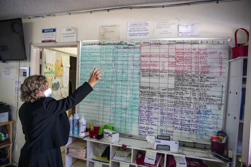 Continental Funeral Home director Magda Maldonado on Dec. 20 looks over a board with dozens of names of the dead who have not yet been buried or cremated in East Los Angeles.(Brian van der Brug/Los Angeles Times)