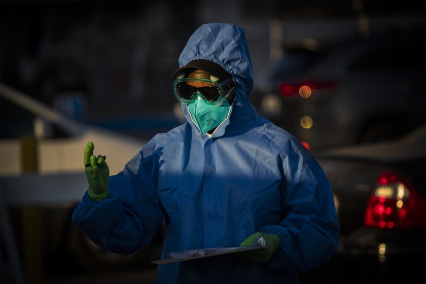 A healthcare worker hands out coronavirus tests at Veterans Memorial Stadium at Long Beach City College on Dec. 9.(Allen J. Schaben / Los Angeles Times)