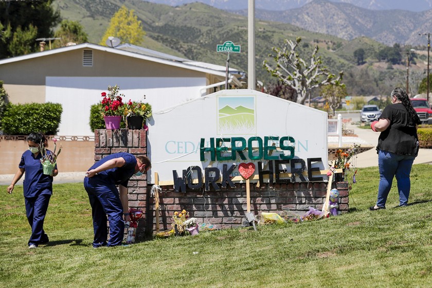 Staff members at Cedar Mountain Post Acute in Yucaipa spruce up a toppled sign that was put up by members of the community to show their support for the nursing staff in 2020.(Irfan Khan / Los Angeles Times)