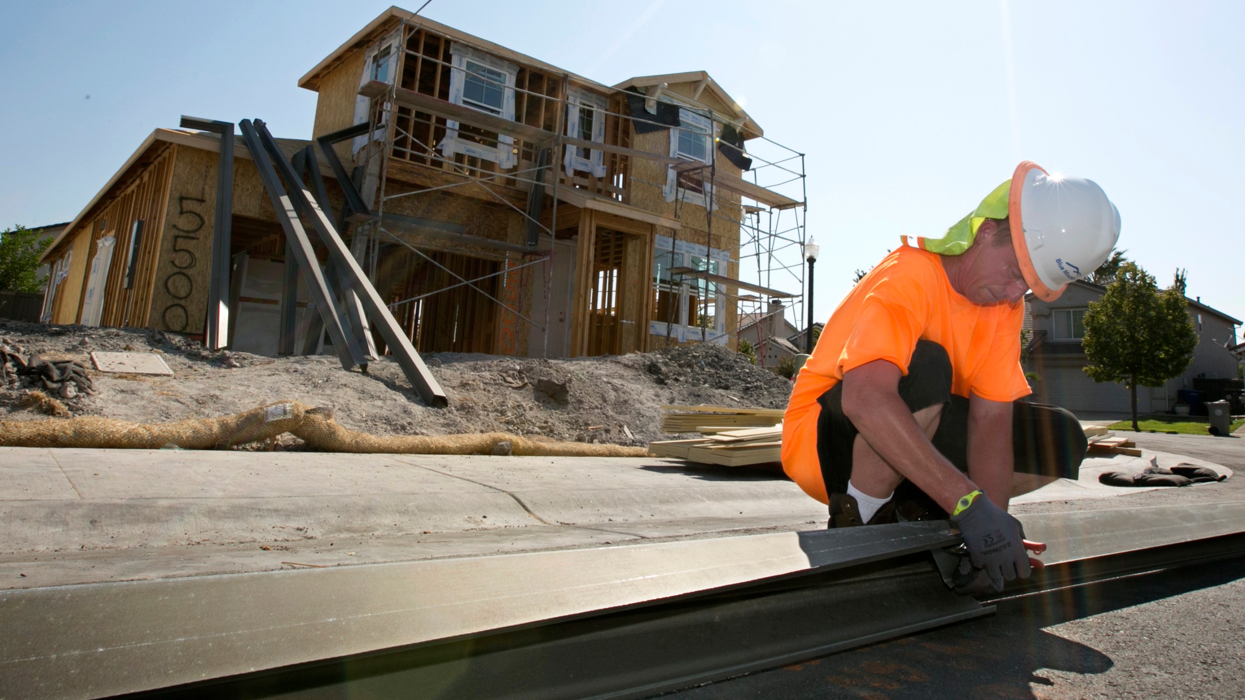 In this photo taken Aug. 16, 2017, sheet metal worker Benjamin Voget prepares to install a gutter on a home under construction in Sacramento. (Rich Pedroncelli / Associated Press)