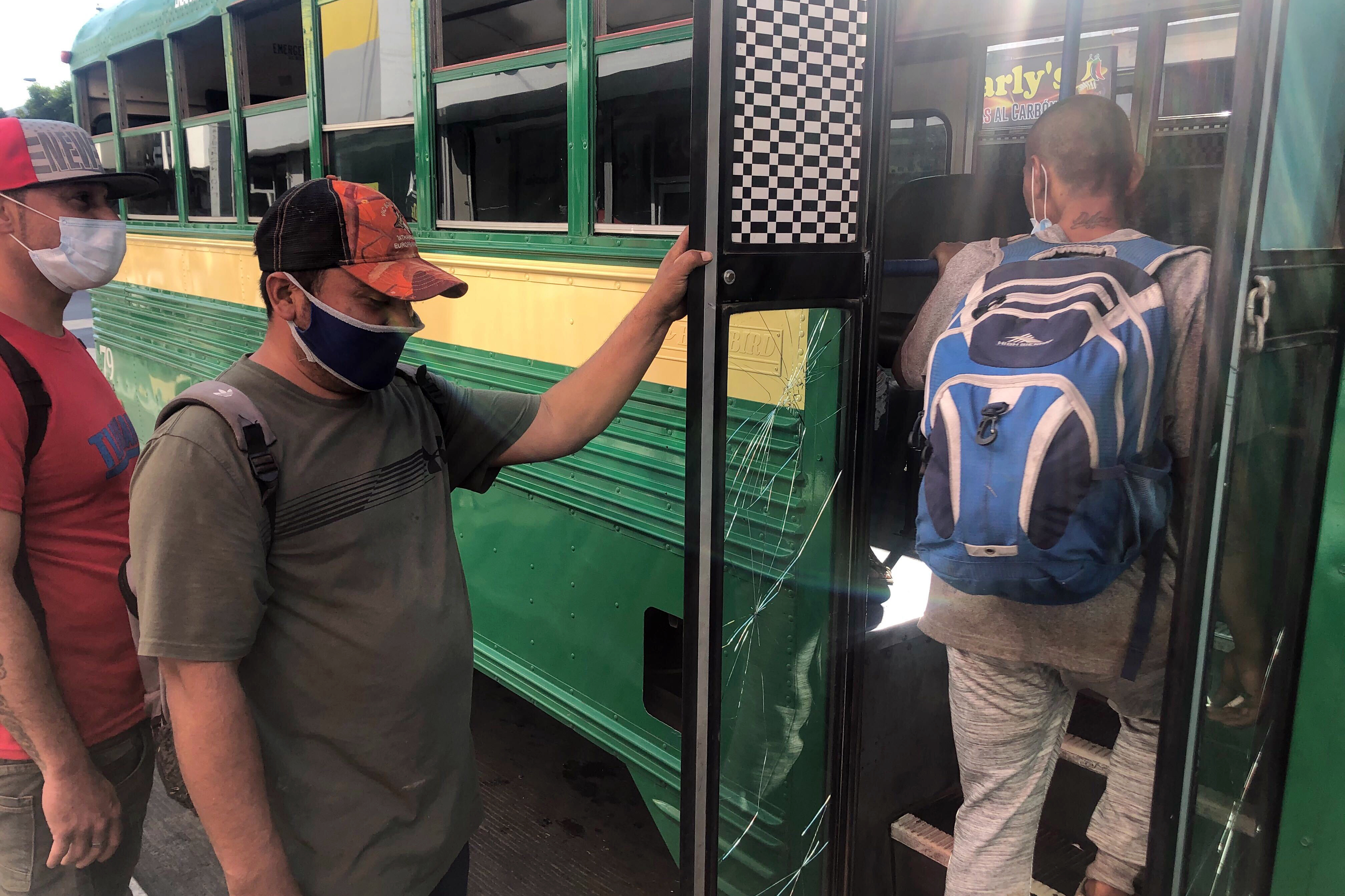 Expelled migrants board a city bus in Tijuana, Mexico, Oct. 8, 2020. (AP Photo/Elliot Spagat)