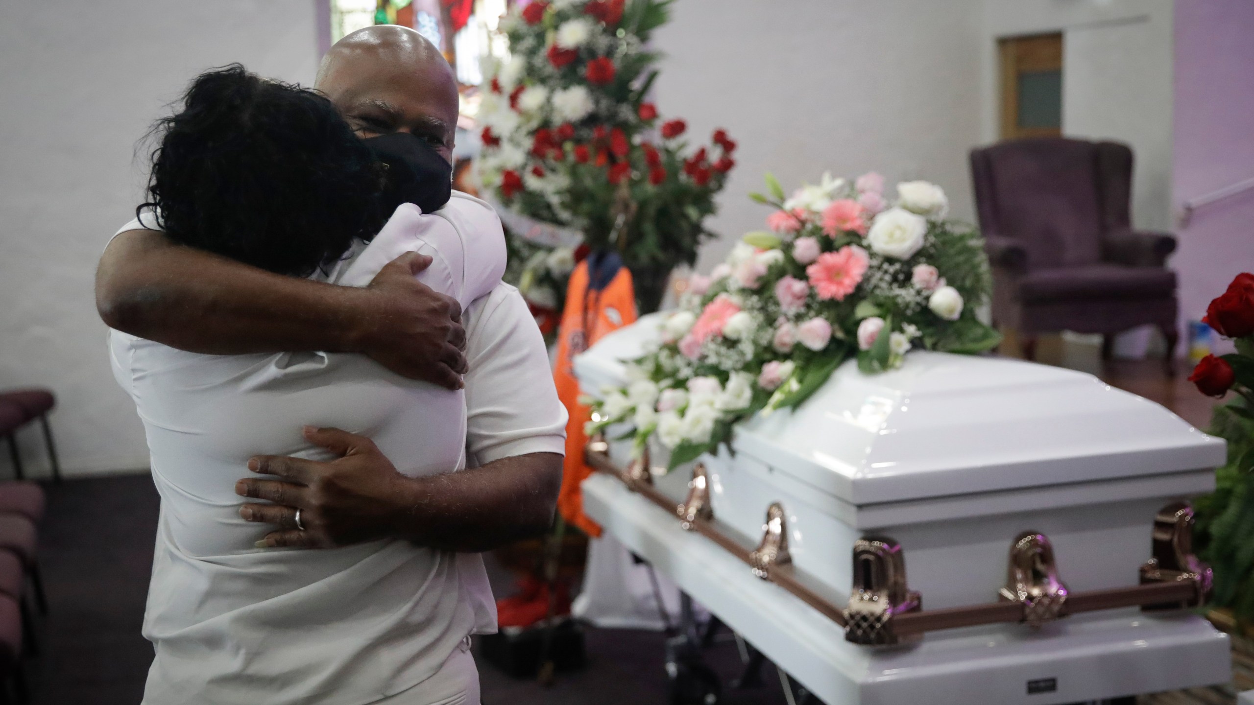 In this July 21, 2020, file photo, Darryl Hutchinson, facing camera, is hugged by a relative during a funeral service for Lydia Nunez, who was Hutchinson's cousin at the Metropolitan Baptist Church in Los Angeles. Nunez died from COVID-19. (AP Photo/Marcio Jose Sanchez, File)