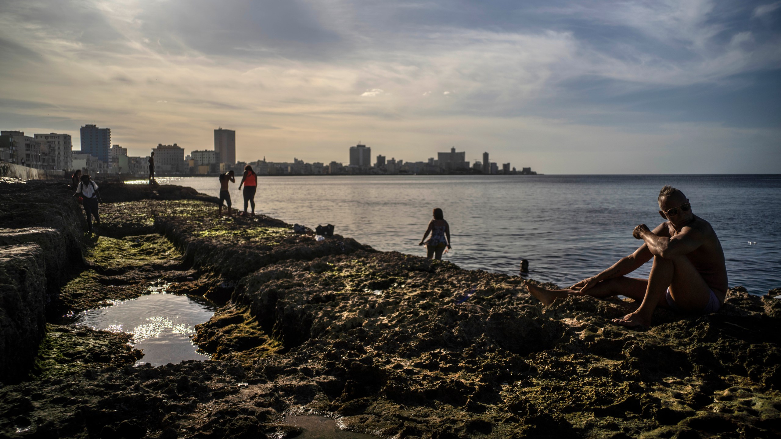 People take a sunbath at sunset on the Malecon in Havana, Cuba, Friday, Jan 1, 2021. (AP Photo/Ramon Espinosa)