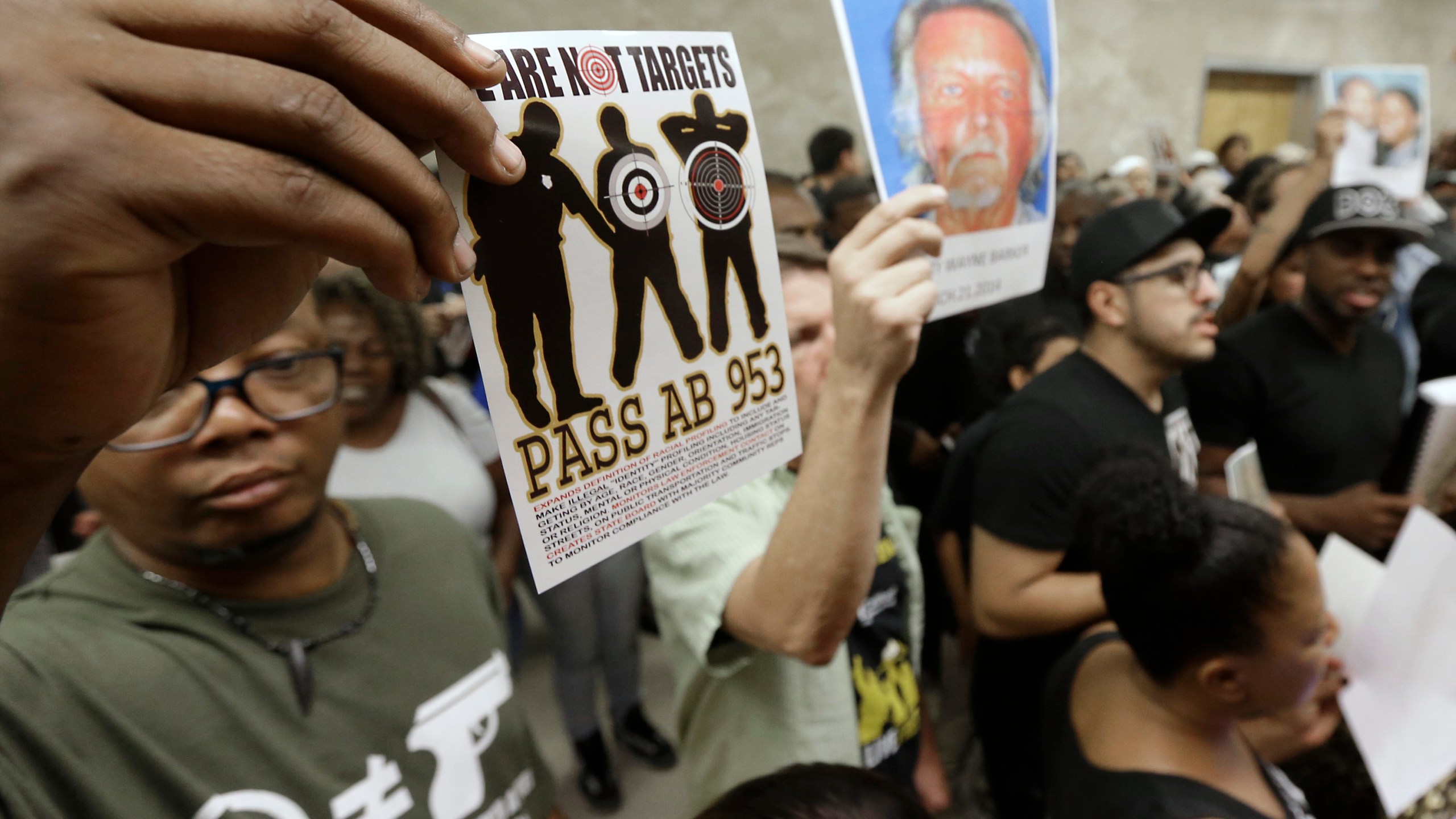 In this Sept. 2, 2015, photo protestors shouting "Black Lives Matter" hold up photos of people they claim are the victims of police violence as they block the hallway outside the governor's office in Sacramento while successfully demanding the passage of AB953. (Rich Pedroncelli / Associated Press)