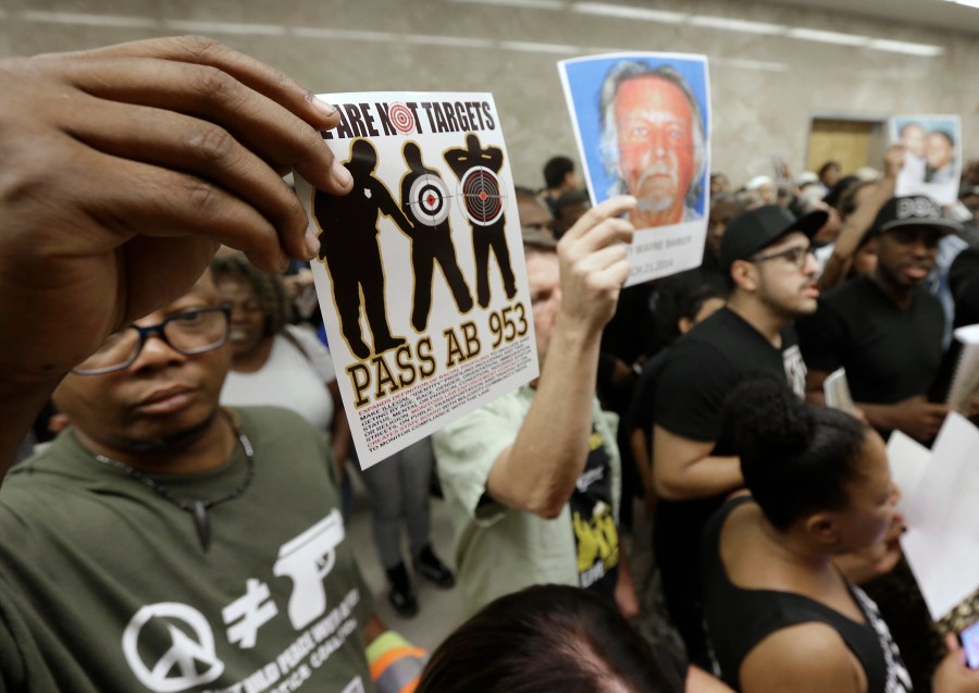 In this Sept. 2, 2015, photo protestors shouting "Black Lives Matter" hold up photos of people they claim are the victims of police violence as they block the hallway outside the governor's office in Sacramento while successfully demanding the passage of AB953. (Rich Pedroncelli / Associated Press)