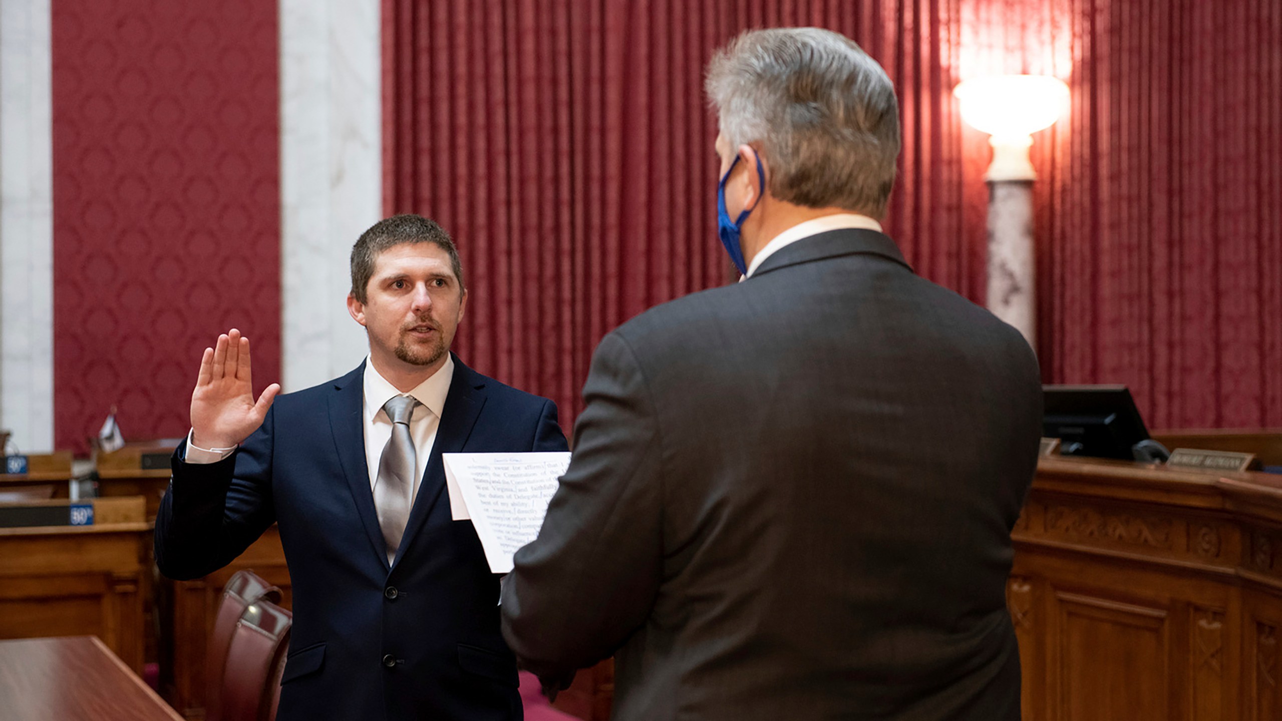 West Virginia House of Delegates member Derrick Evans, left, is given the oath of office Dec. 14, 2020, in the House chamber at the state Capitol in Charleston, W.Va. Evans recorded video of himself and fellow supporters of President Donald Trump storming the U.S. Capitol in Washington, D.C., on Wednesday, Jan. 6, 2021 prompting calls for his resignation and thousands of signatures on an online petition advocating his removal. (Perry Bennett/West Virginia Legislature via AP)