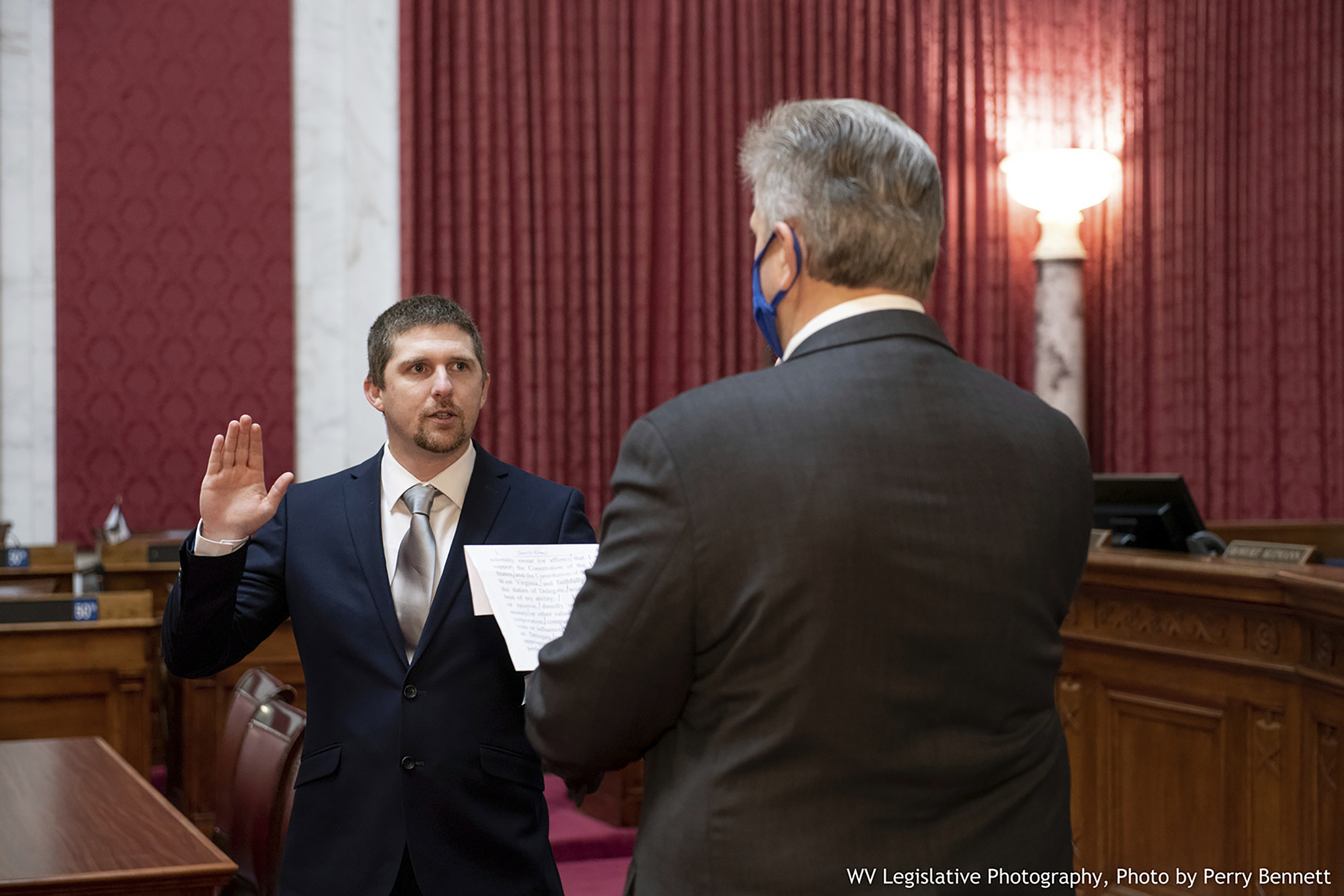 West Virginia House of Delegates member Derrick Evans, left, is given the oath of office Dec. 14, 2020, in the House chamber at the state Capitol in Charleston, W.Va. Evans recorded video of himself and fellow supporters of President Donald Trump storming the U.S. Capitol in Washington, D.C., on Wednesday, Jan. 6, 2021 prompting calls for his resignation and thousands of signatures on an online petition advocating his removal. (Perry Bennett/West Virginia Legislature via AP)