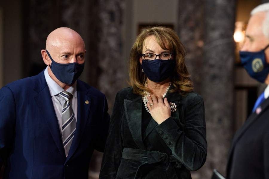 In this Dec. 2, 2020, file photo, Sen. Mark Kelly, D-Ariz., talks with his wife former Rep. Gabby Giffords, D-Ariz., and Vice President Mike Pence after participating in a re-enactment of his swearing-in on Capitol Hill in Washington. As a mob laid siege to the U.S. Capitol this week, former Rep. Gabby Giffords could only wait nervously for news about her husband, Mark Kelly, who was barely a month into his job as a newly elected senator from Arizona. A decade earlier it was Kelly enduring the excruciating wait for news about Giffords, who was shot in the head in an attempted assassination that, like Wednesday's siege, shocked the nation and prompted a reckoning about the state of politics and discourse in the United States. (Nicholas Kamm/Pool via AP, File)