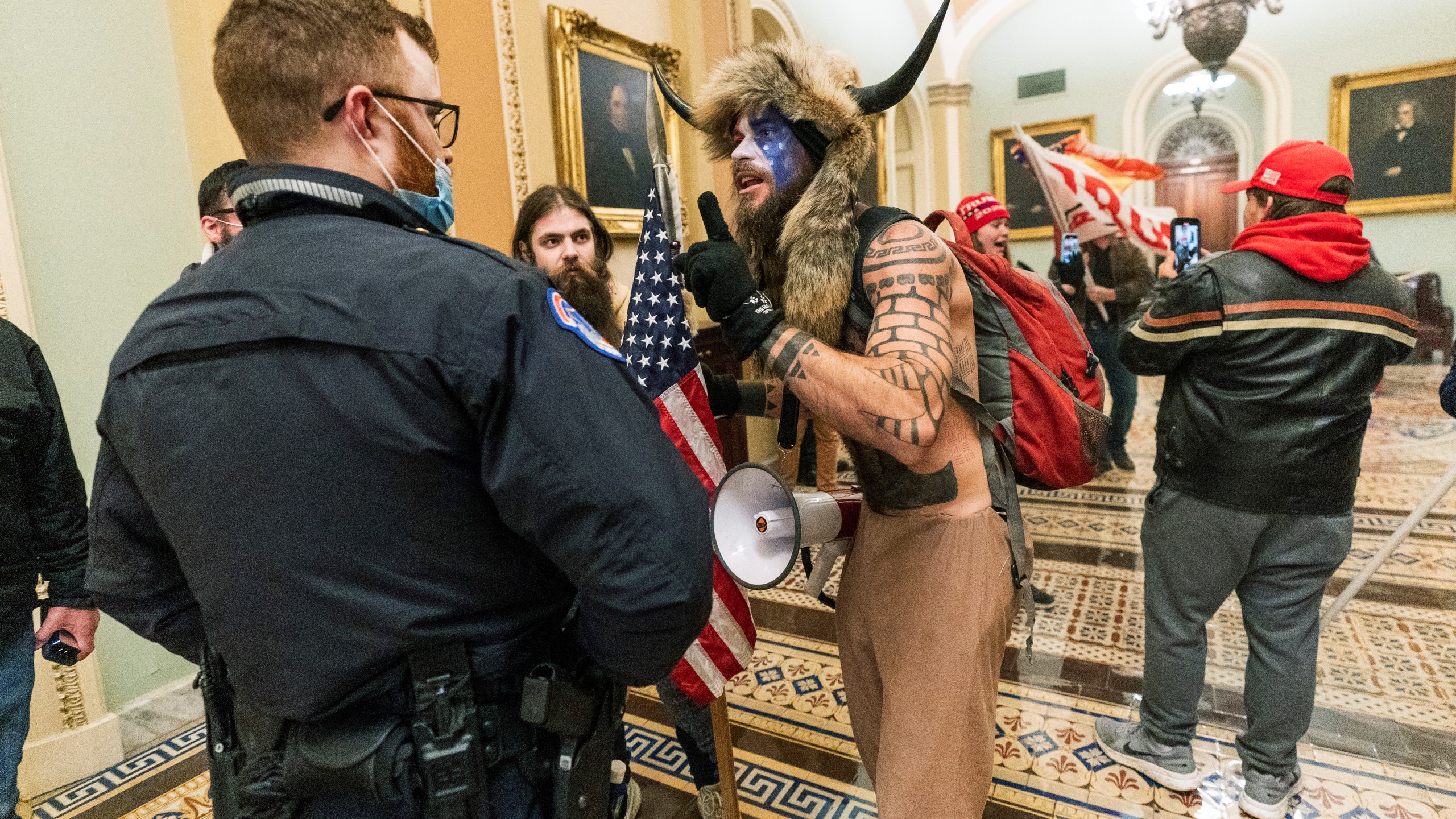 In this Jan. 6, 2021, file photo supporters of President Donald Trump are confronted by U.S. Capitol Police officers outside the Senate Chamber inside the Capitol in Washington. An Arizona man seen in photos and video of the mob wearing a fur hat with horns was also charged Saturday in Wednesday's chaos. Jacob Anthony Chansley, who also goes by the name Jake Angeli, was taken into custody Saturday, Jan. 9. (AP Photo/Manuel Balce Ceneta, File)