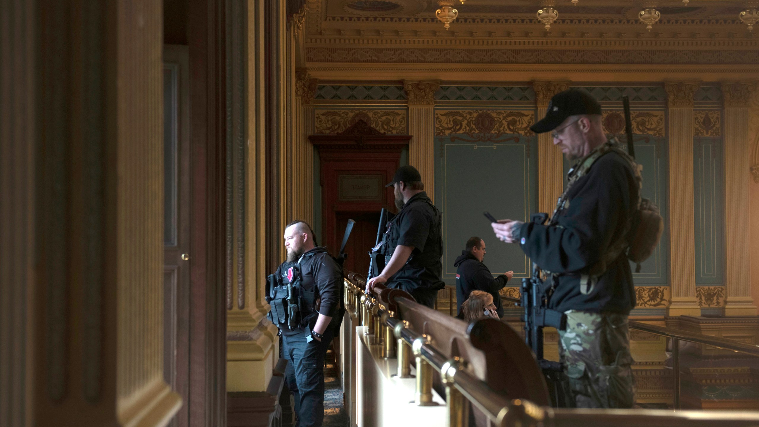 In this April 30, 2020, file photo, armed members of a militia group watch the protest outside while waiting for the Michigan Senate to vote at the Capitol in Lansing, Mich. Michigan has banned the open carry of guns in the state Capitol a week after an armed mob rioted in the U.S. Capitol and following an attempt to storm the statehouse last year. (Nicole Hester/MLive.com/Ann Arbor News via AP File)