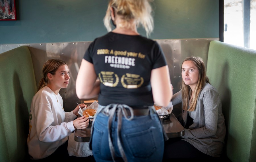 In this Jan. 11, 2021, file photo, Grace Mathre, server at Longfellow Grill, checks on University of St. Thomas students Lundsey Schulz and Maren Daggett in Minneapolis. (Glen Stubbe/Star Tribune via Associated Press)