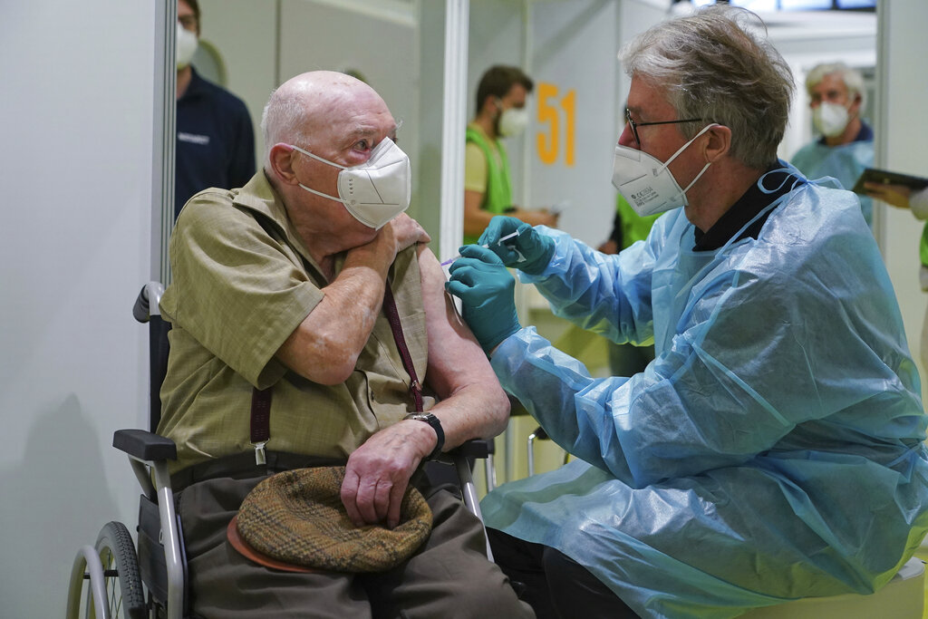 A doctor inoculates Herri Rehfeld, 92, against the new coronavirus with the Pfizer/BioNTech vaccine at the vaccination center at the Messe Berlin trade fair grounds on the center's opening day in Berlin, Germany, Monday, Jan. 18, 2021. (Sean Gallup/Getty Images via AP, Pool)