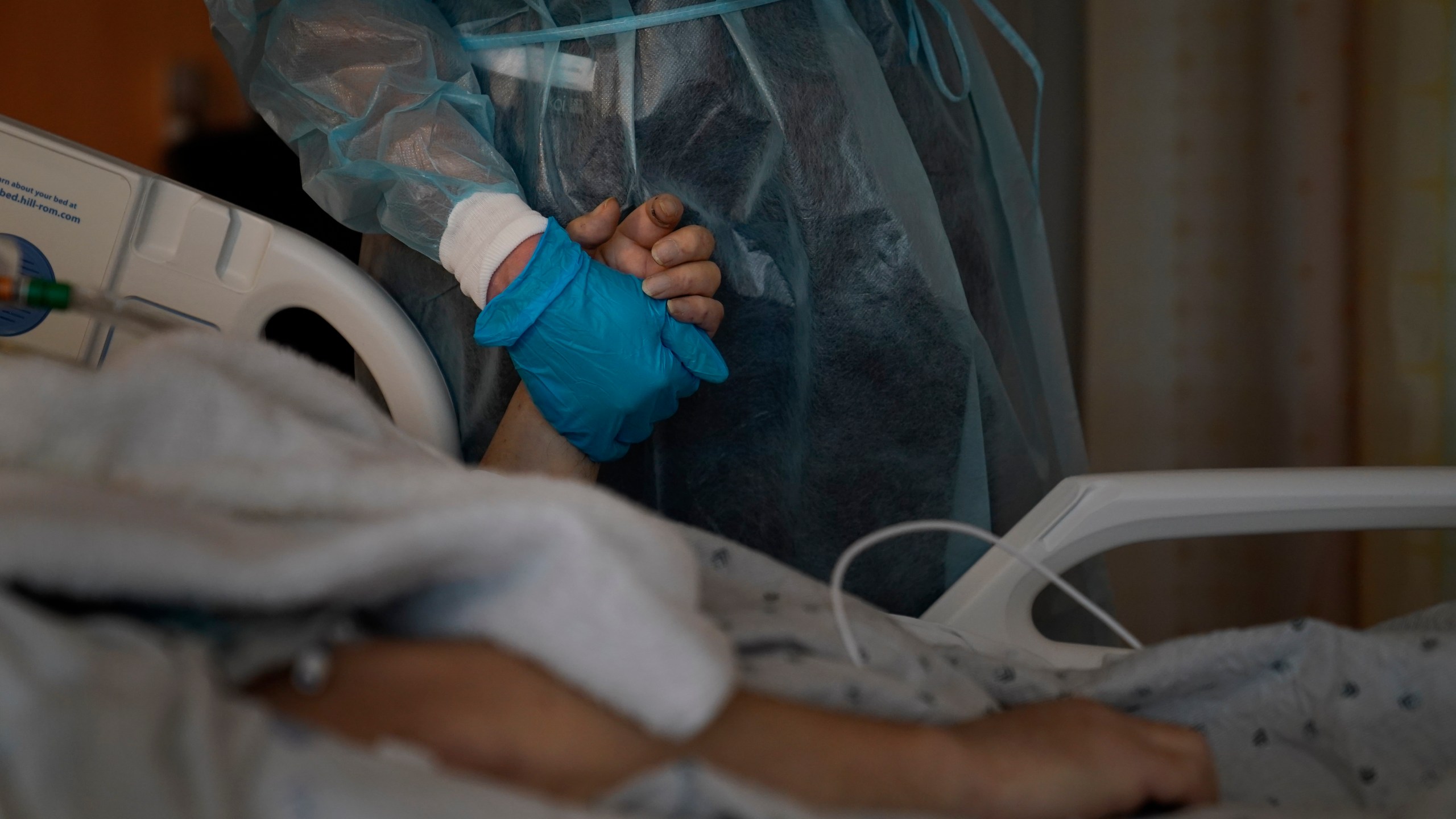 Chaplain Kristin Michealsen holds the hand of a deceased COVID-19 patient while talking on the phone with the patient's family member at Providence Holy Cross Medical Center in the Mission Hills section of Los Angeles on Jan. 9, 2021. (Jae C. Hong / Associated Press)